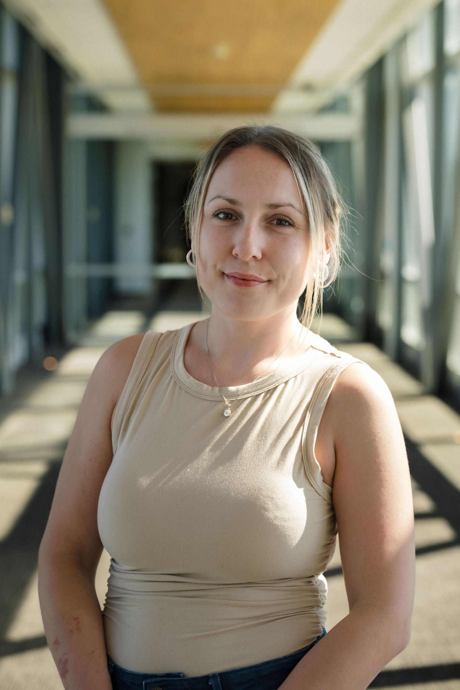 Professional headshot in bright modern office hallway.