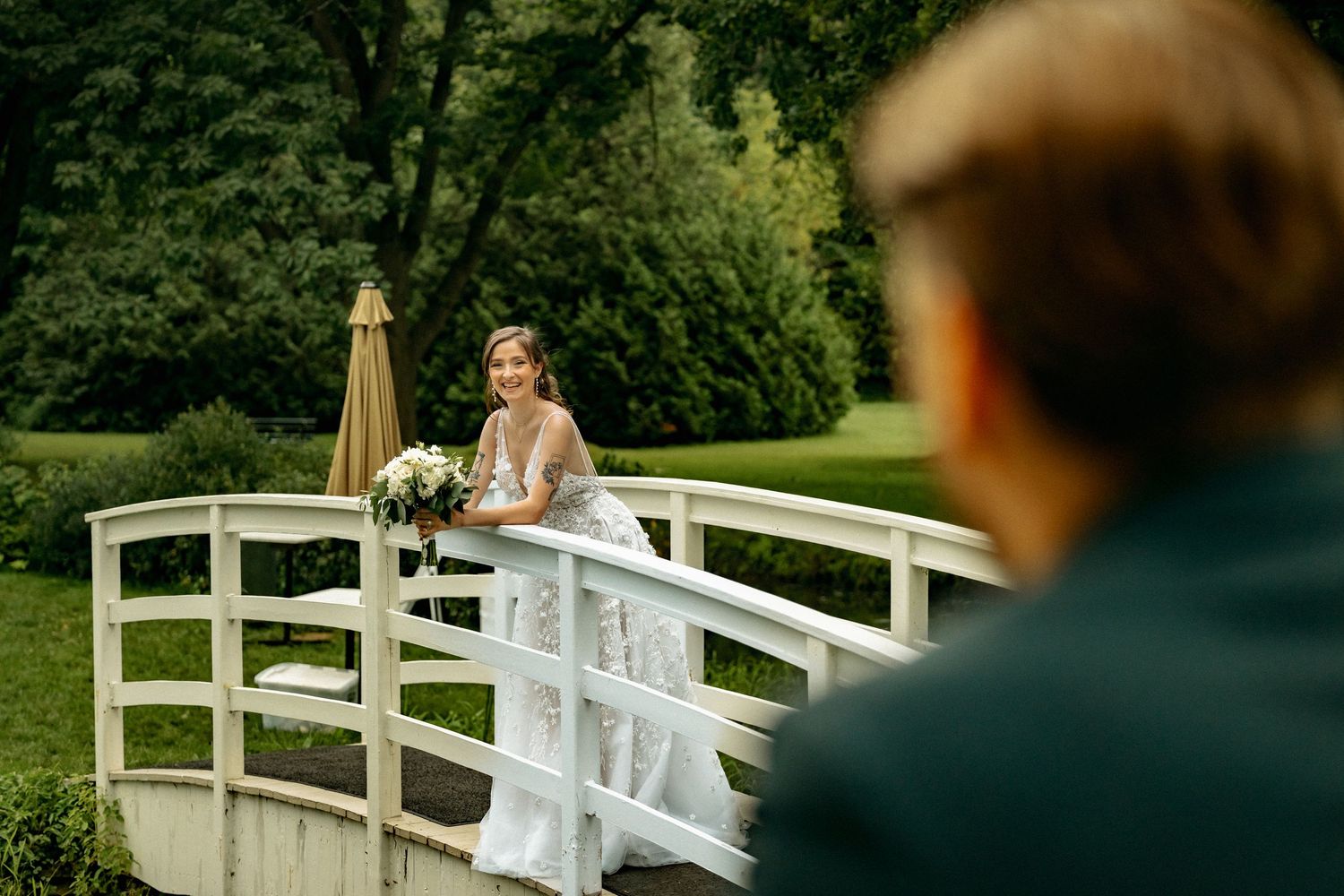 A couple walks across a white bridge during their wedding photoshoot.