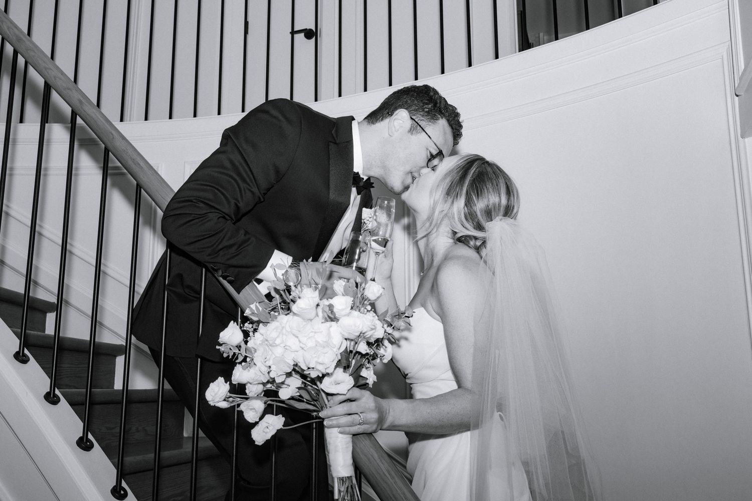 Wedding couple embraces on an elegant staircase in black and white photography.