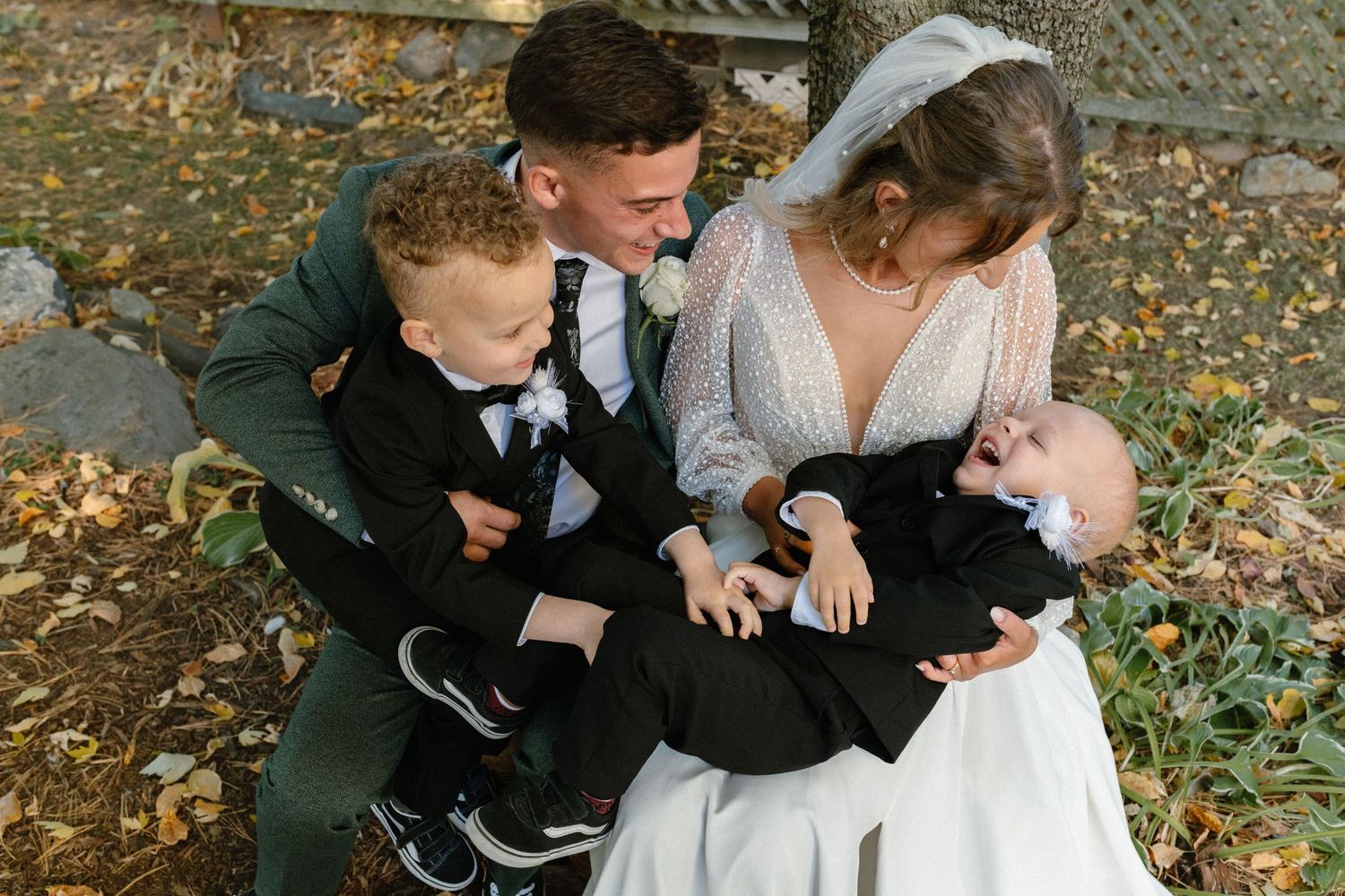 Romantic wedding couple embraces on autumn path surrounded by fallen leaves.