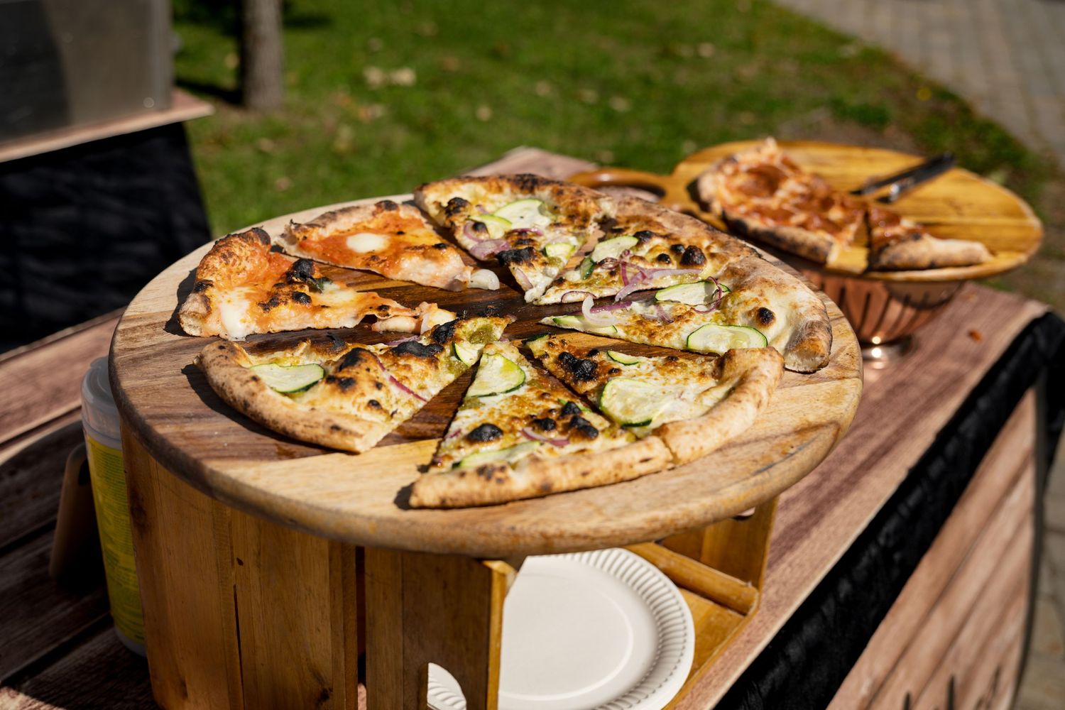 Fresh gourmet pizzas served on wooden cutting boards at outdoor dining setting.
