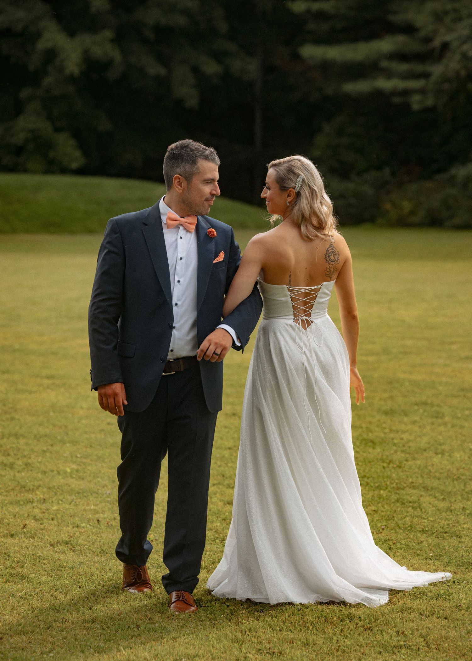 Couple walking together on a grassy lawn during an outdoor wedding photoshoot.