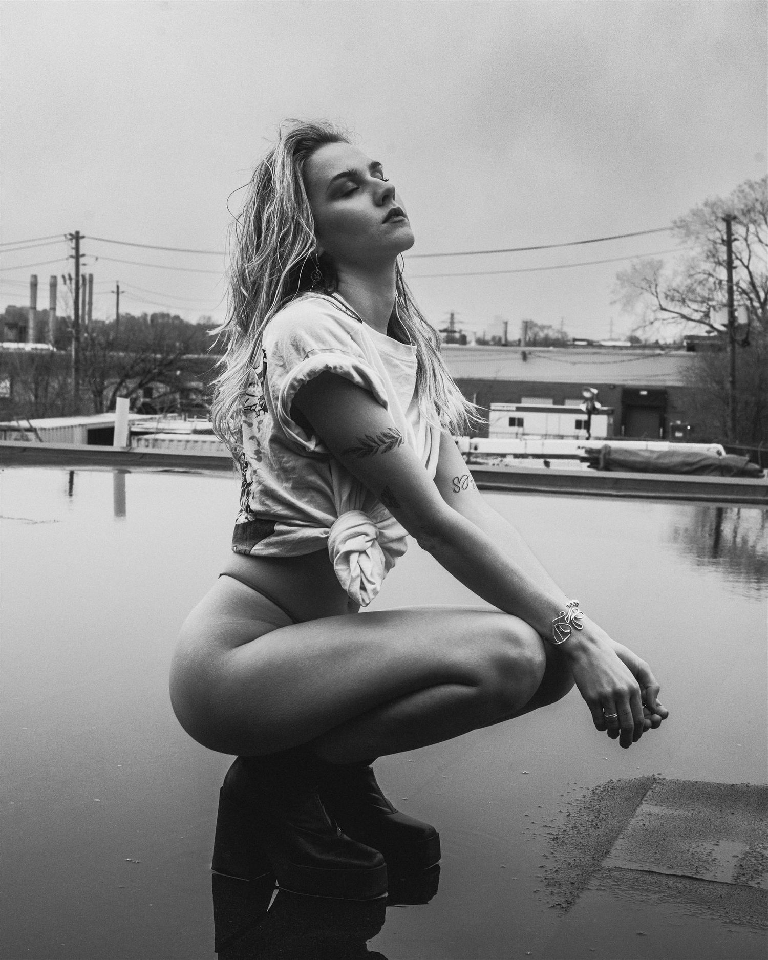 Black and white outdoor portrait series near water with overcast sky.