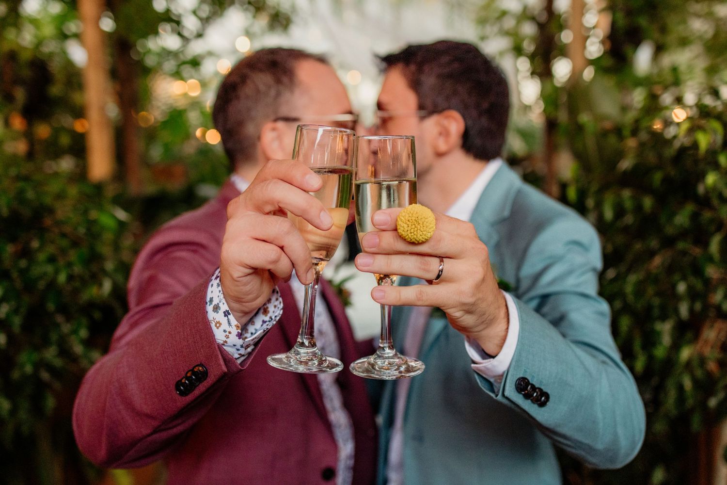 Two people sharing drinks and laughing together in an outdoor garden setting.
