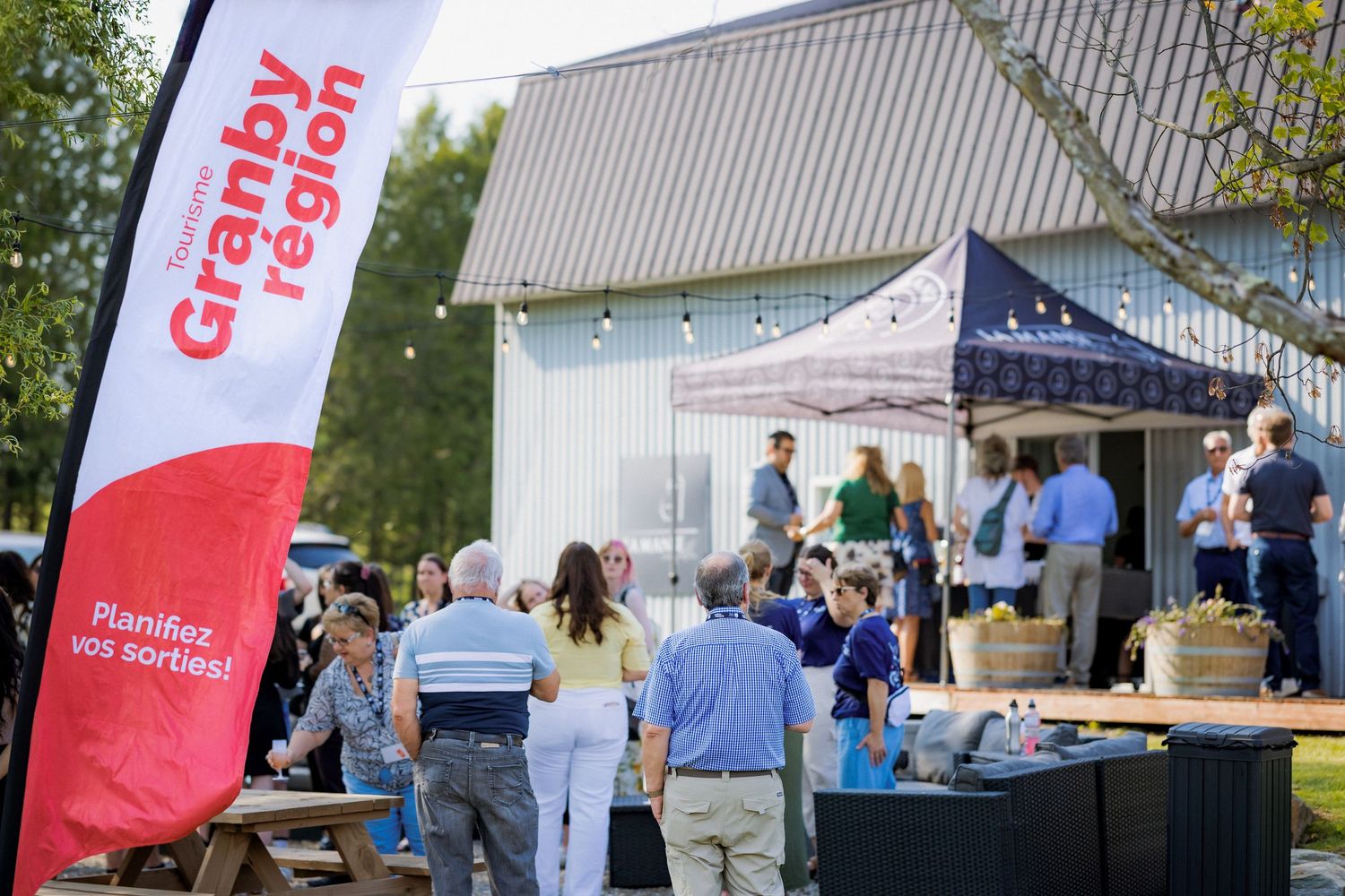 Outdoor event setup with red banners and vendor tents against a rural backdrop.