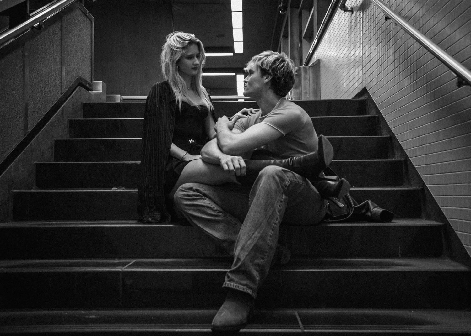 Intimate black and white portrait of couple sitting together on concrete stairs.