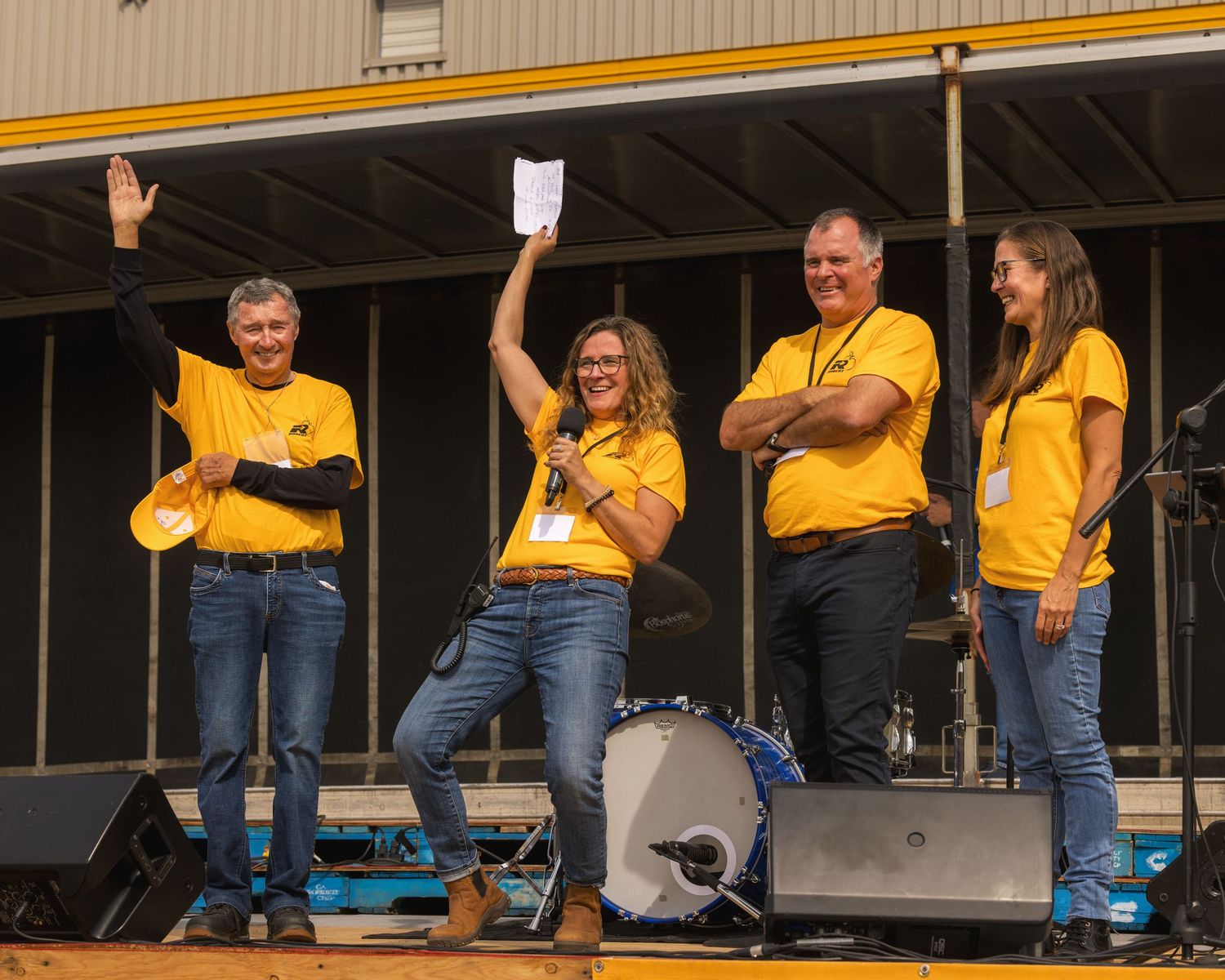 People in yellow shirts performing on an outdoor stage.