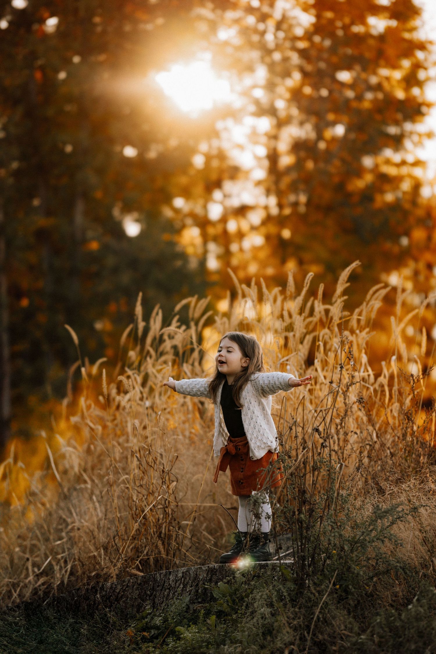 Person standing in golden wheat field at sunset with arms outstretched.
