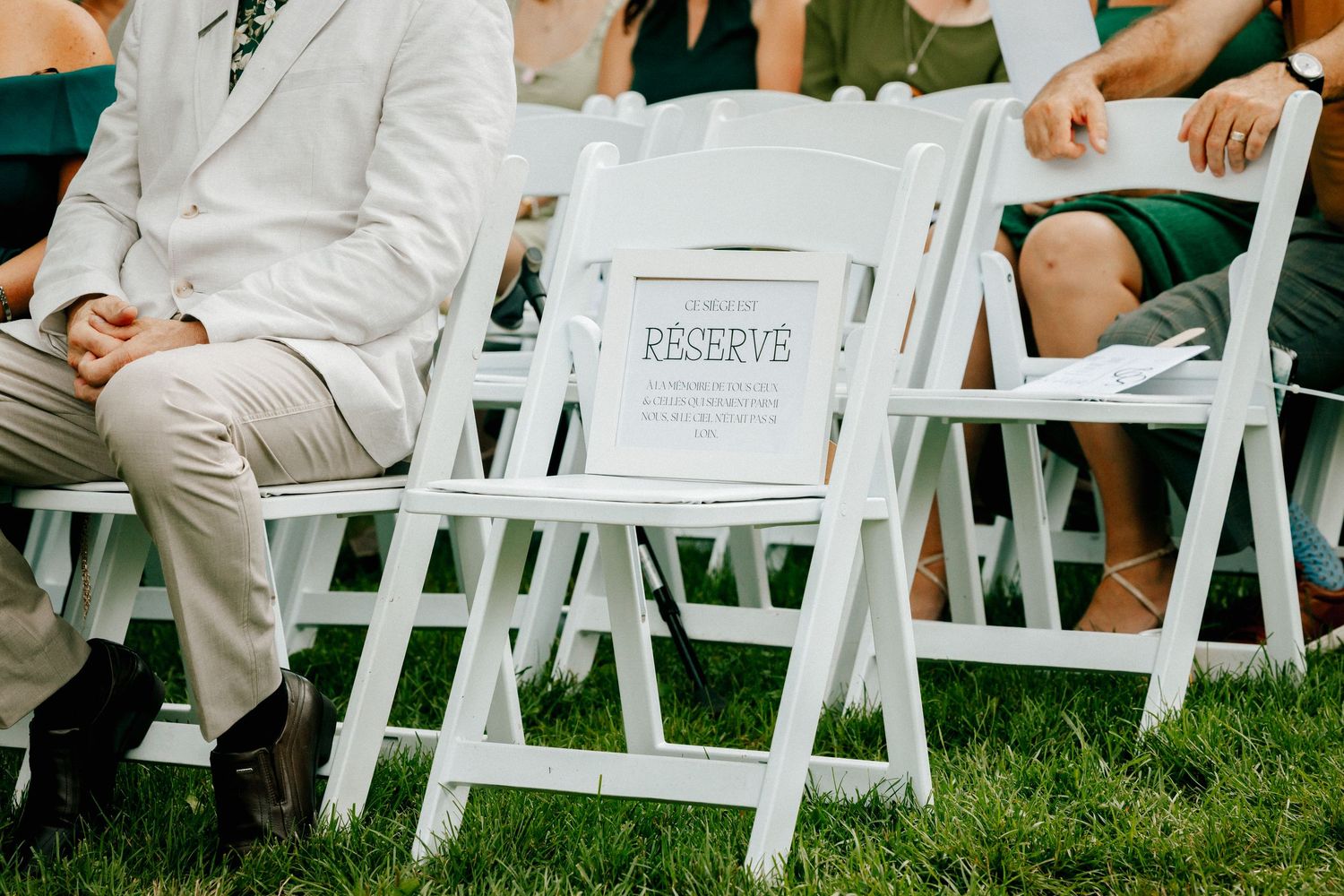 White folding chairs arranged on grass for outdoor wedding ceremony.