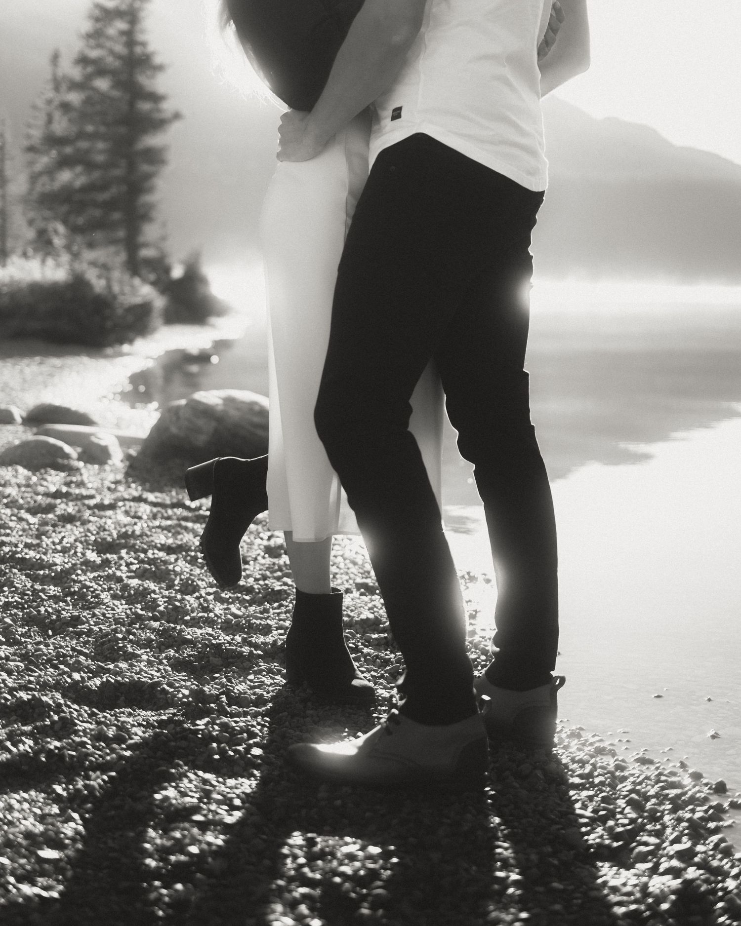Black and white close-up of feet standing on rocky ground in dramatic lighting.