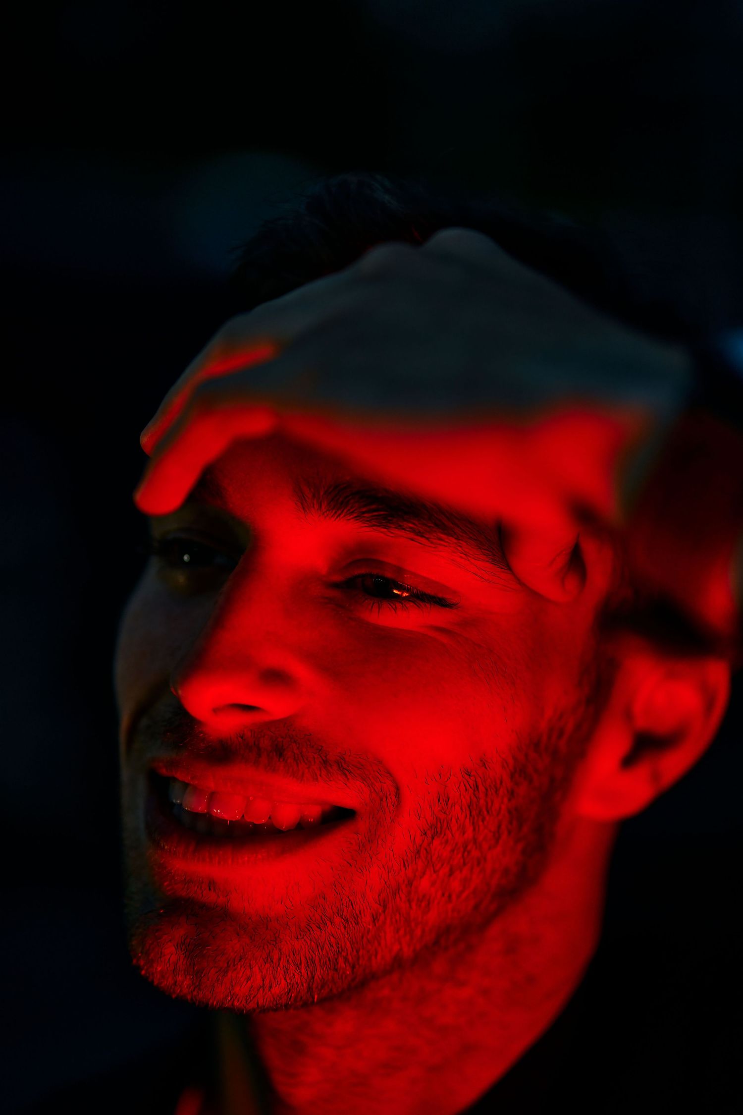 Artistic portrait series bathed in red lighting showing expressive shadows and angles.