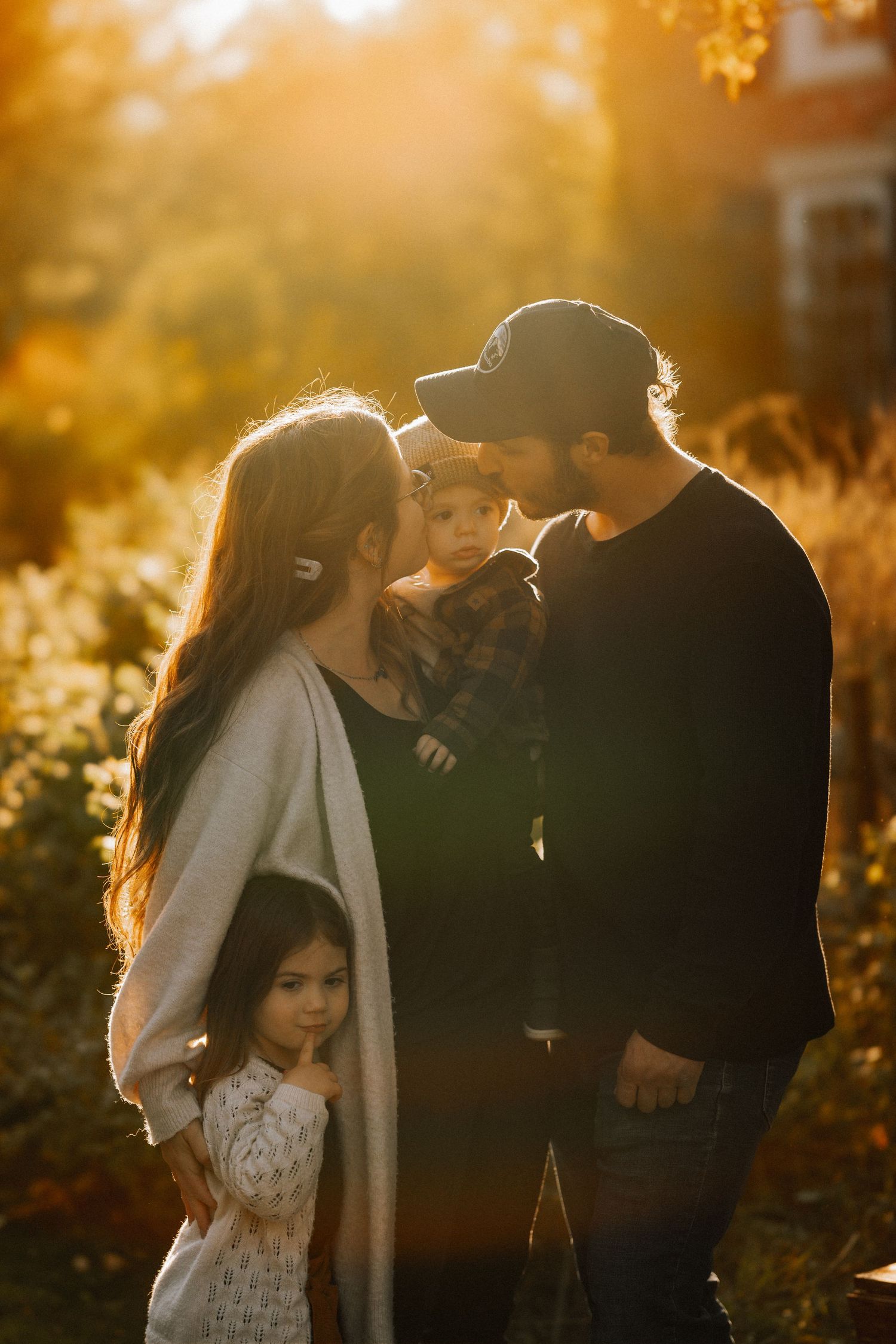 A couple shares an intimate moment in a sunlit field during golden hour with warm autumn colors.