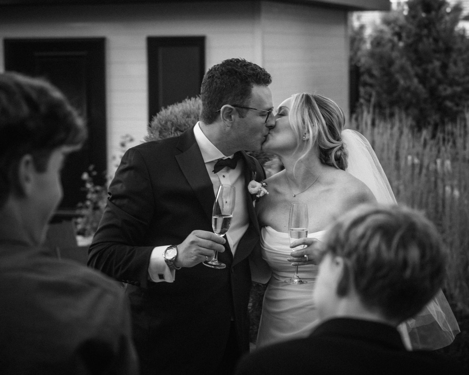 Black and white wedding moment shared with guests holding champagne glasses.