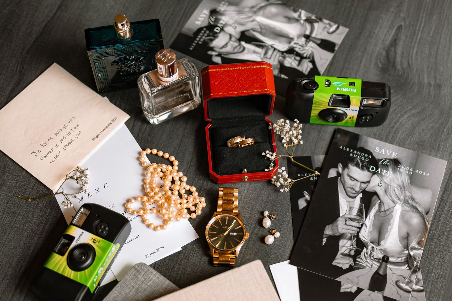 Wedding details including jewelry, watches, and toy cars arranged on a dark surface.