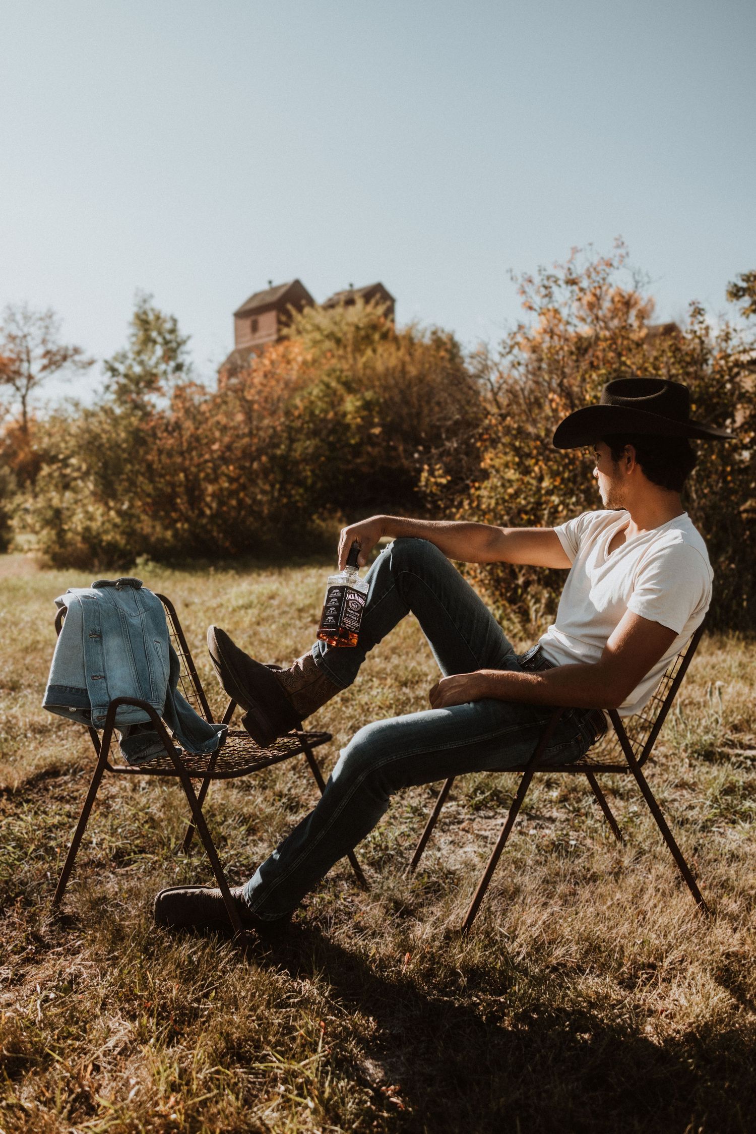 Person relaxing in camping chair on grassy hillside during golden hour.