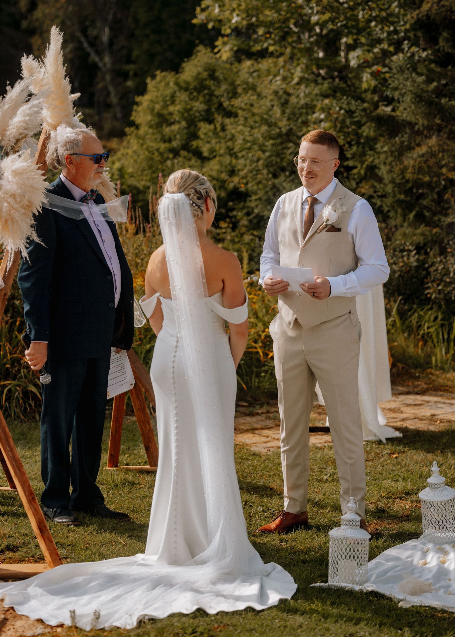 Outdoor wedding ceremony on grass with white decor and mountain views.