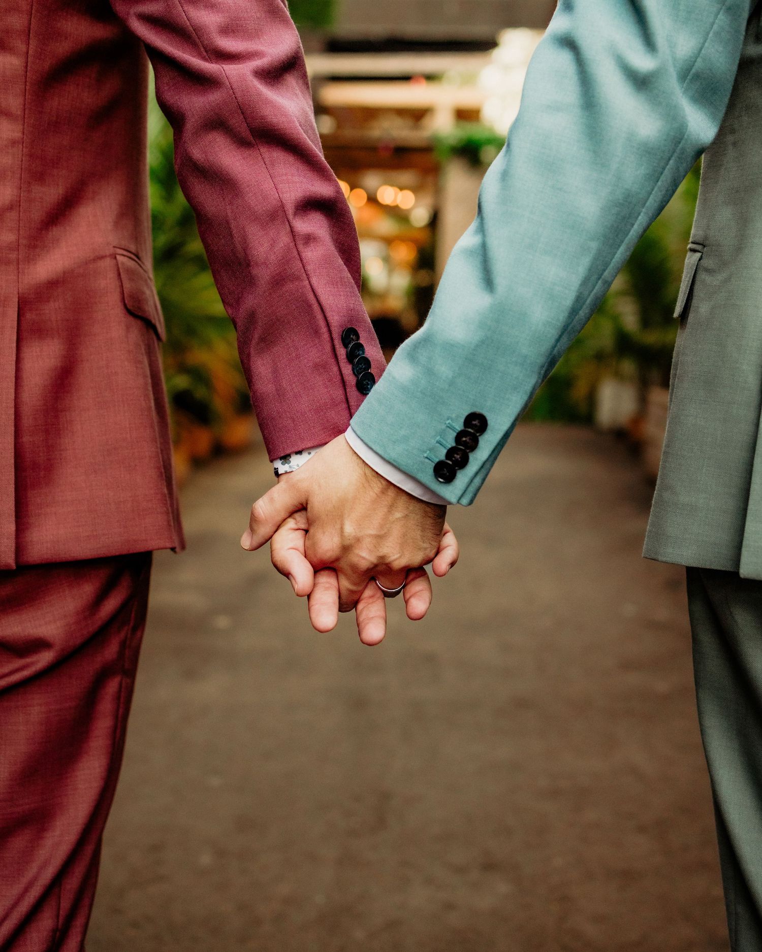 Close-up sequence of hands holding in burgundy and mint colored sleeves.