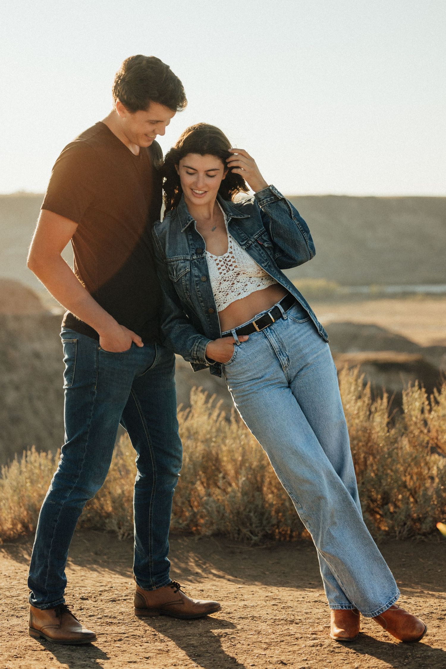 Casual couple in western-inspired outfits sharing a candid moment outdoors.