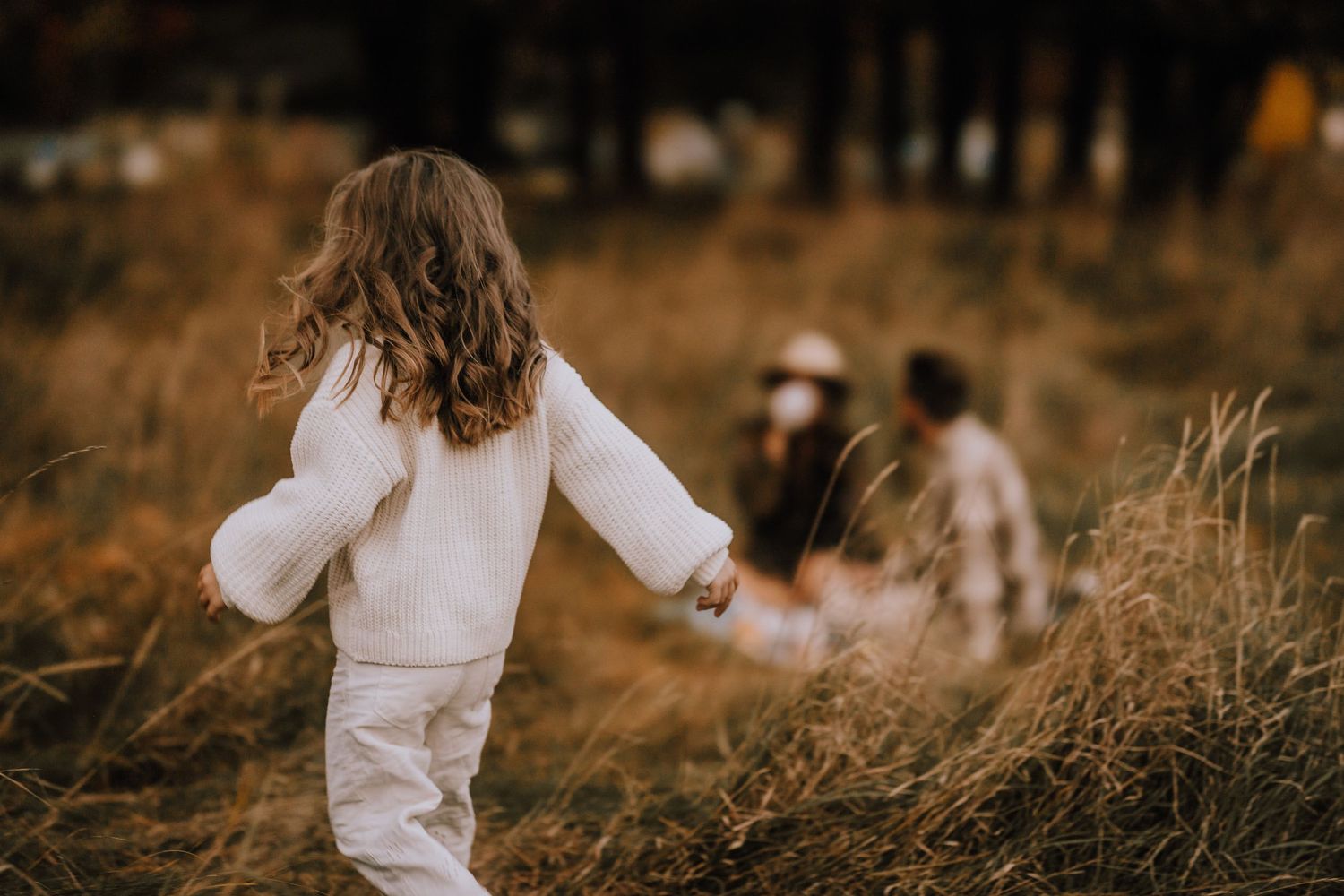 A child in white running through a golden field during autumn.