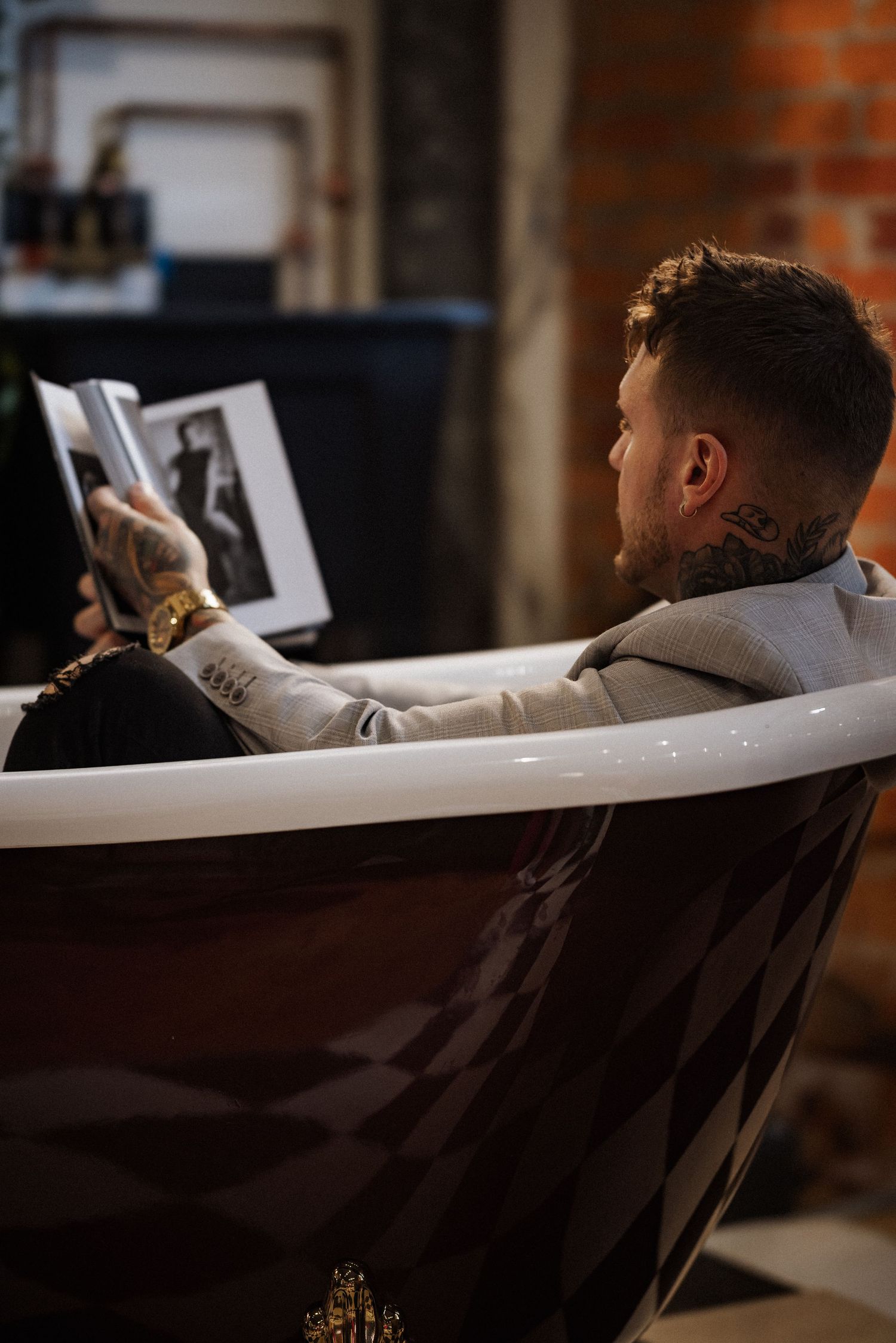 Person relaxing in a white chair while reading in an industrial brick interior.