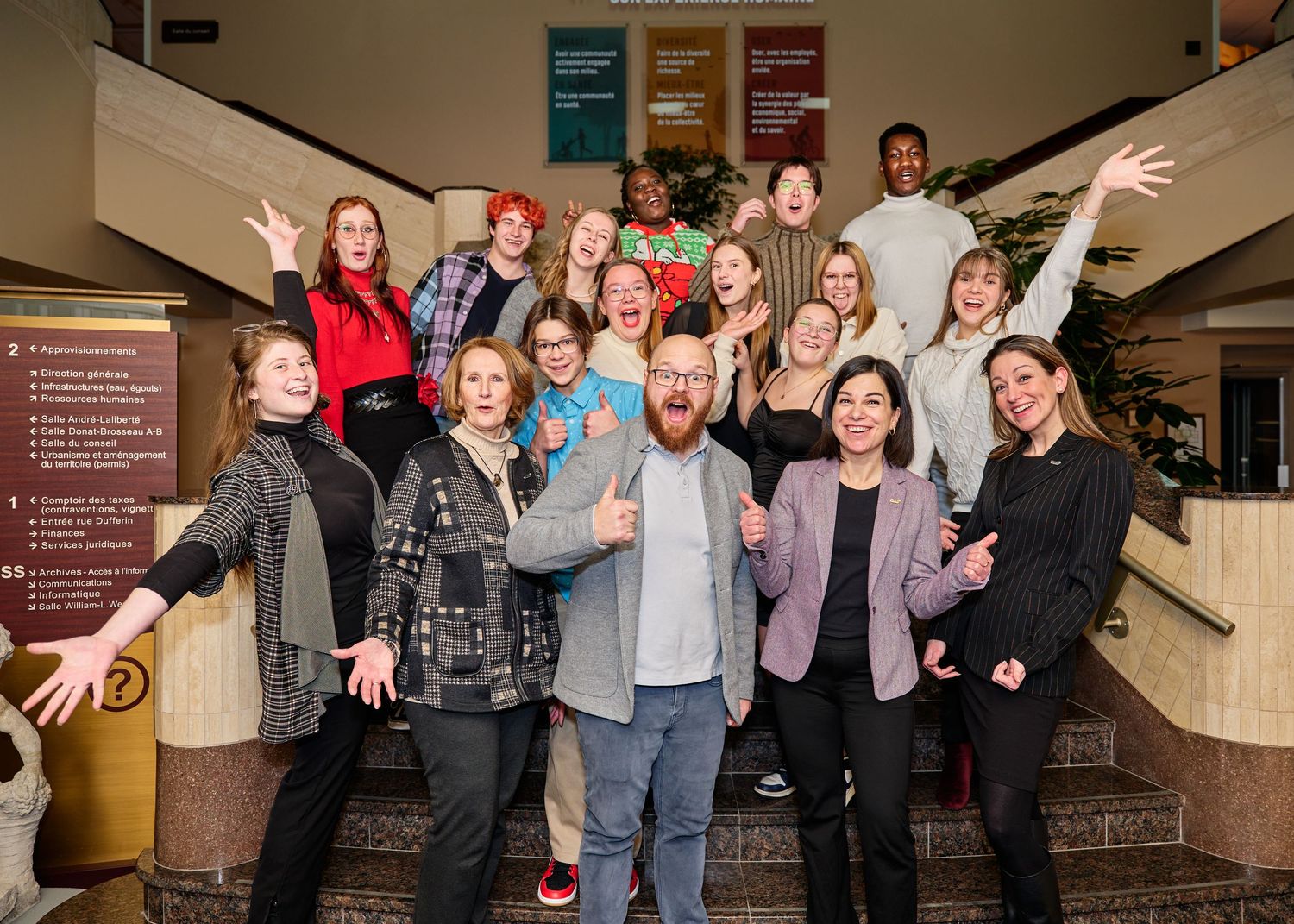 Large group of people posing enthusiastically in an indoor venue.