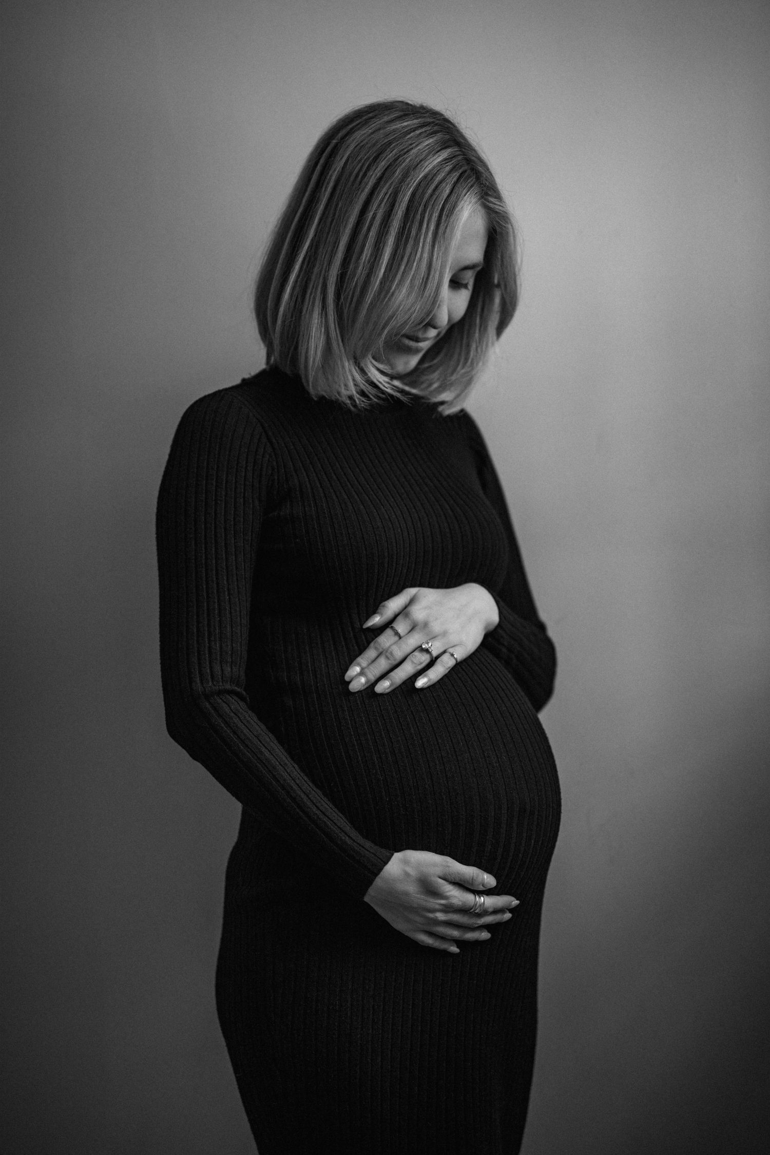 A series of black and white photos showing a pregnant belly in a black sweater.