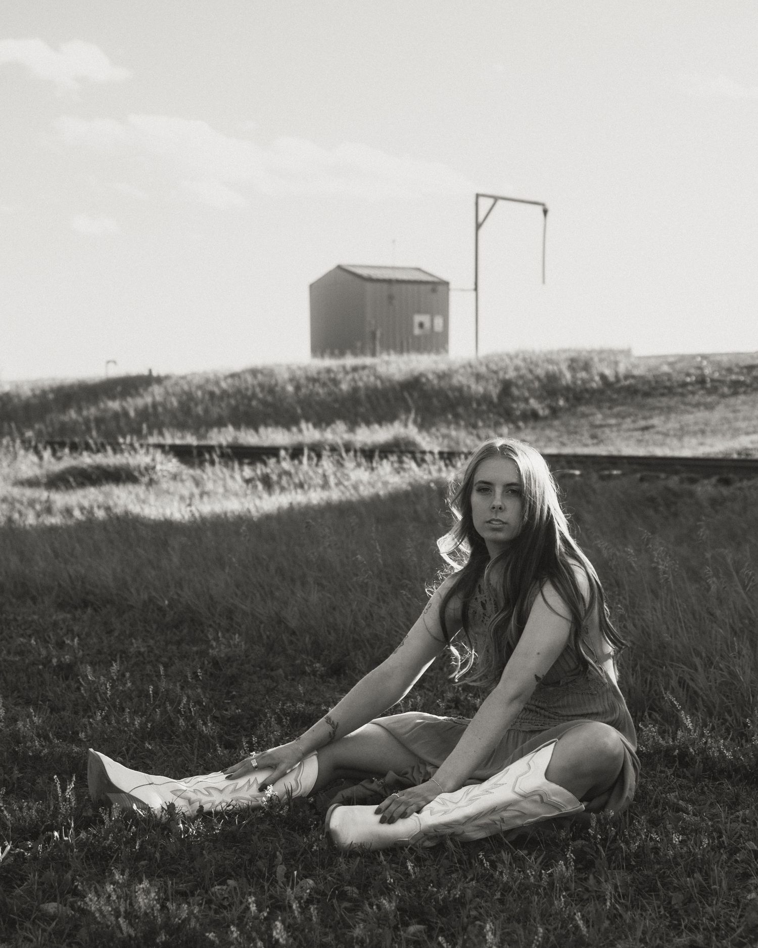 Artistic black and white portrait showing someone reclining on grassy hillside.
