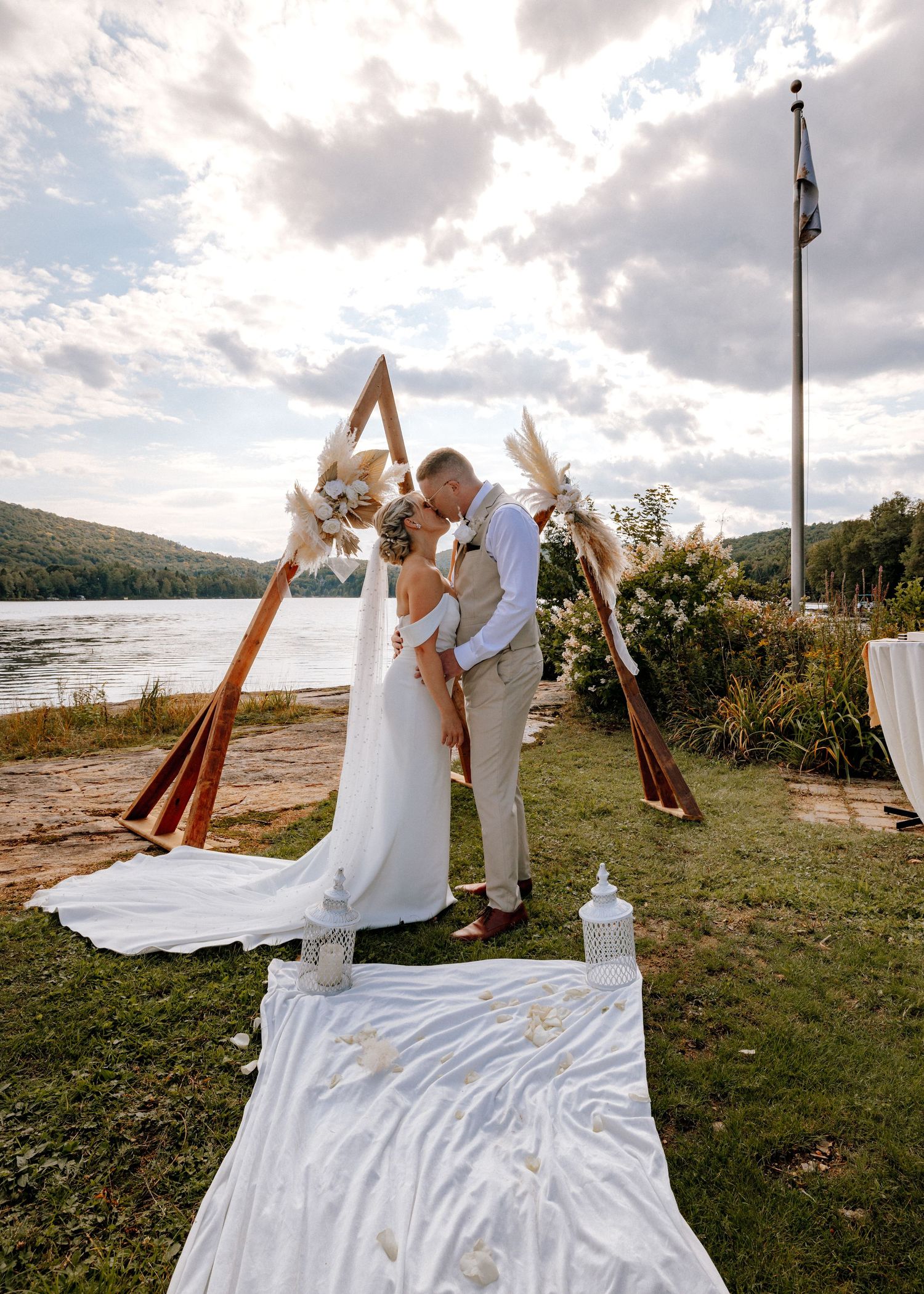 Wedding ceremony takes place on a grassy hill overlooking a scenic waterfront.