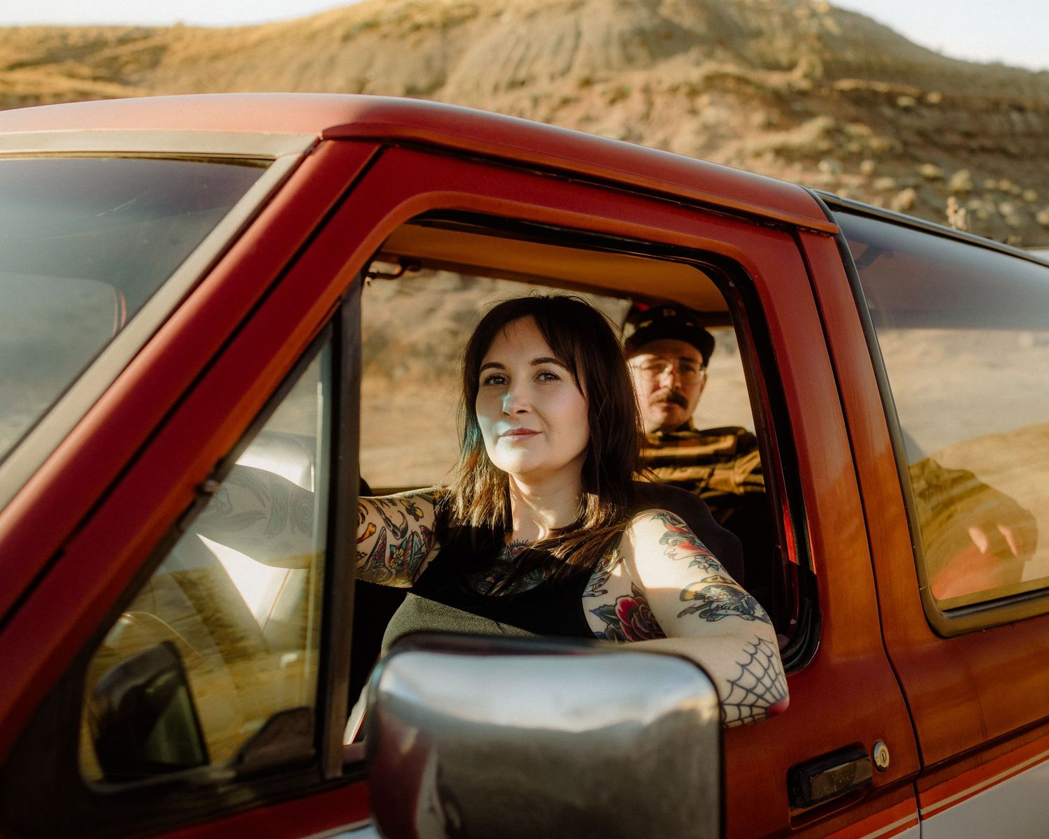 Series of candid shots inside a vintage red pickup truck against desert landscape.