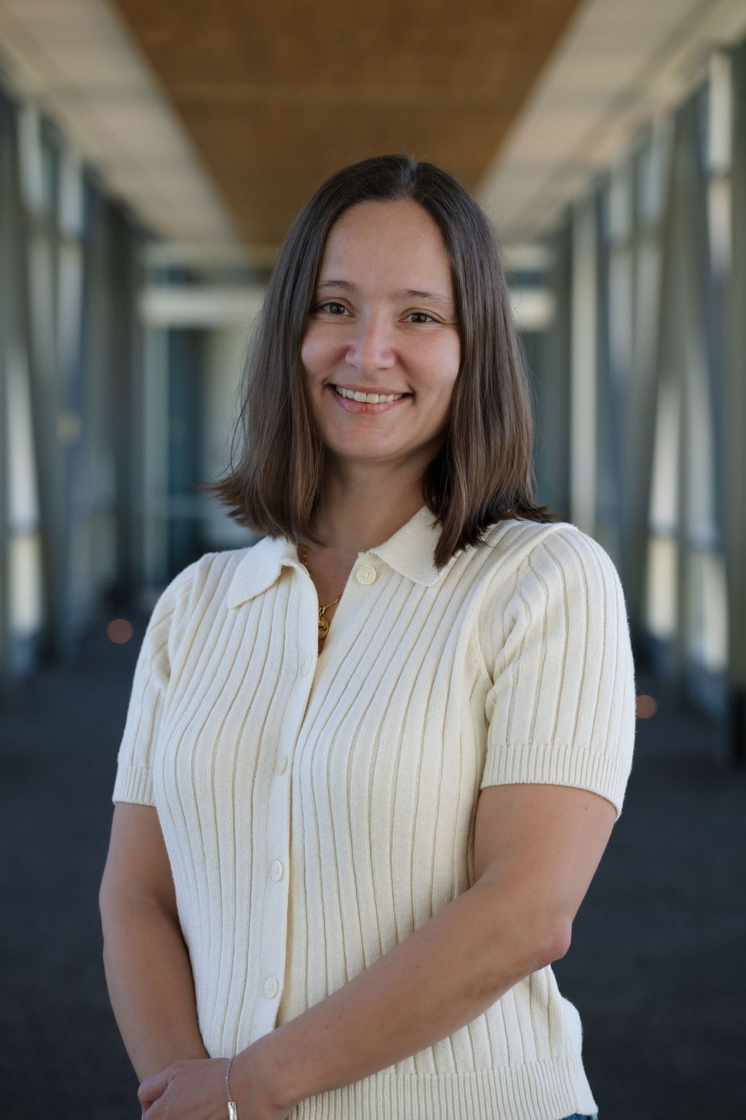 Professional portrait in modern office corridor with natural lighting.