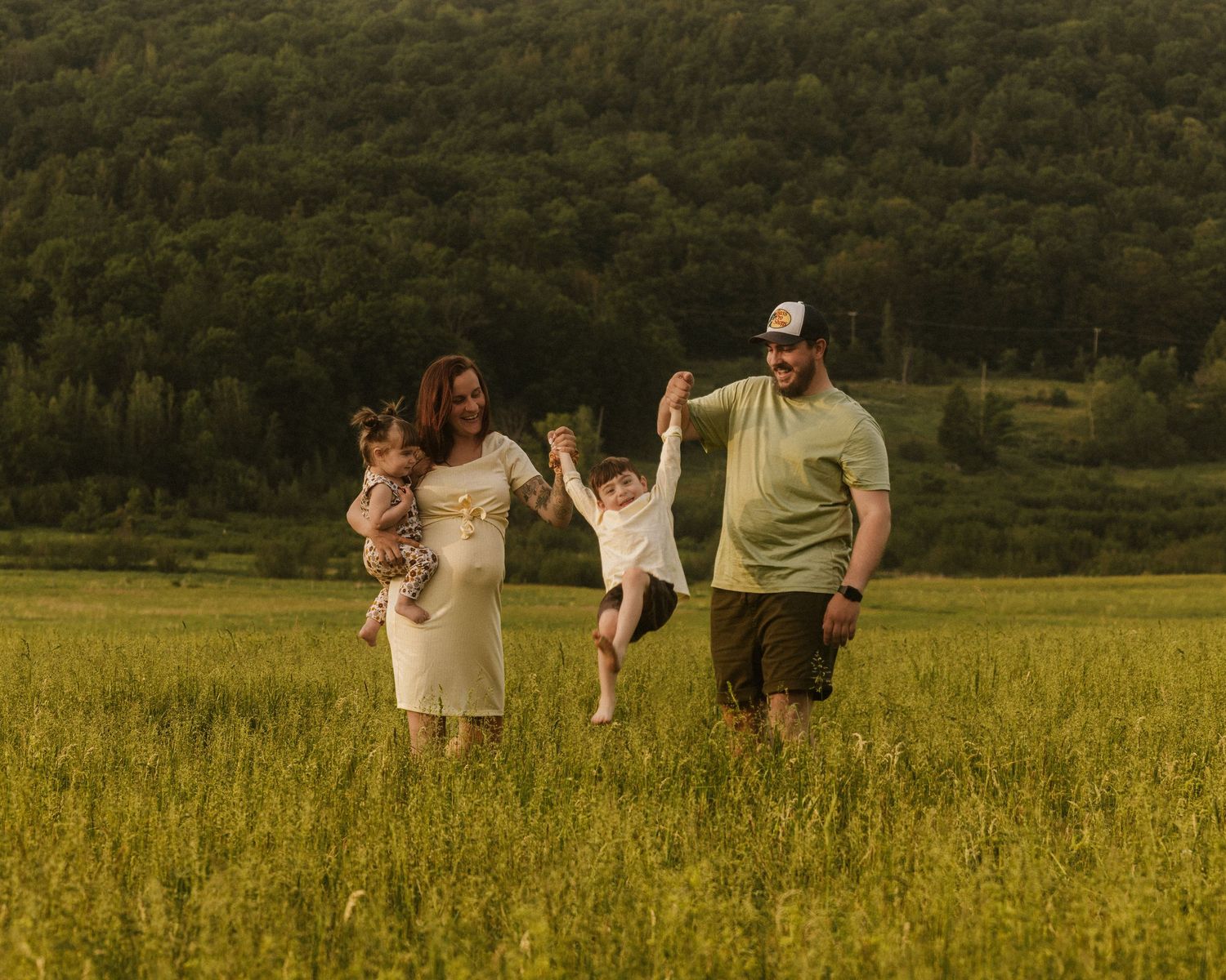 Family walking together through golden wildflower field at sunset.
