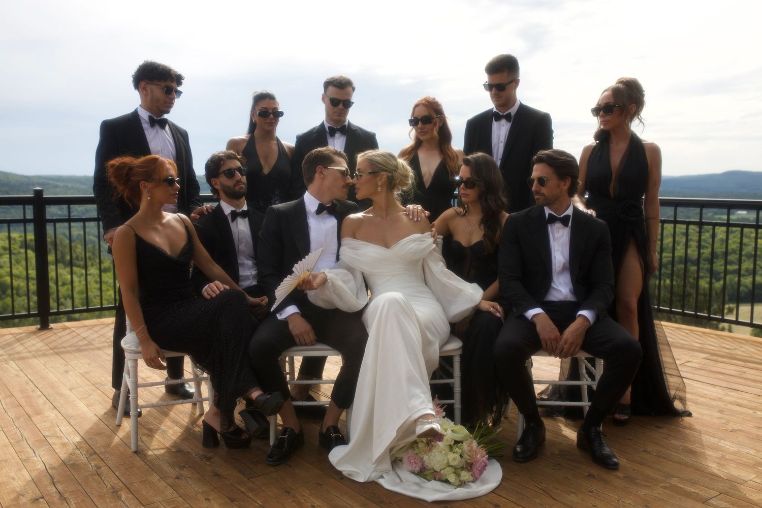 Wedding party gathers on scenic outdoor terrace overlooking mountain landscape.