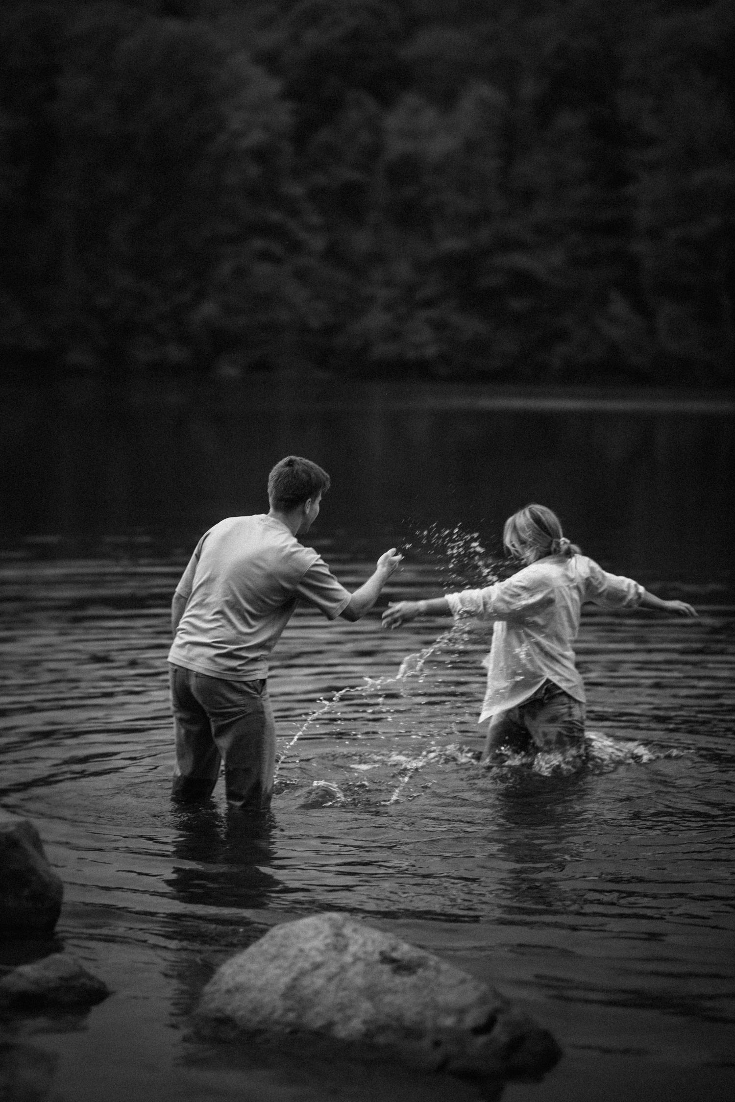 Black and white series of playful couple splashing in lake water.