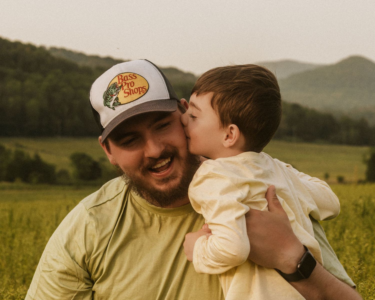 Sweet family moment captured in warm sunlight with mountain views.