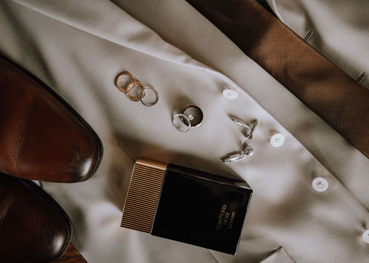 Wedding accessories and rings arranged artistically on white fabric.