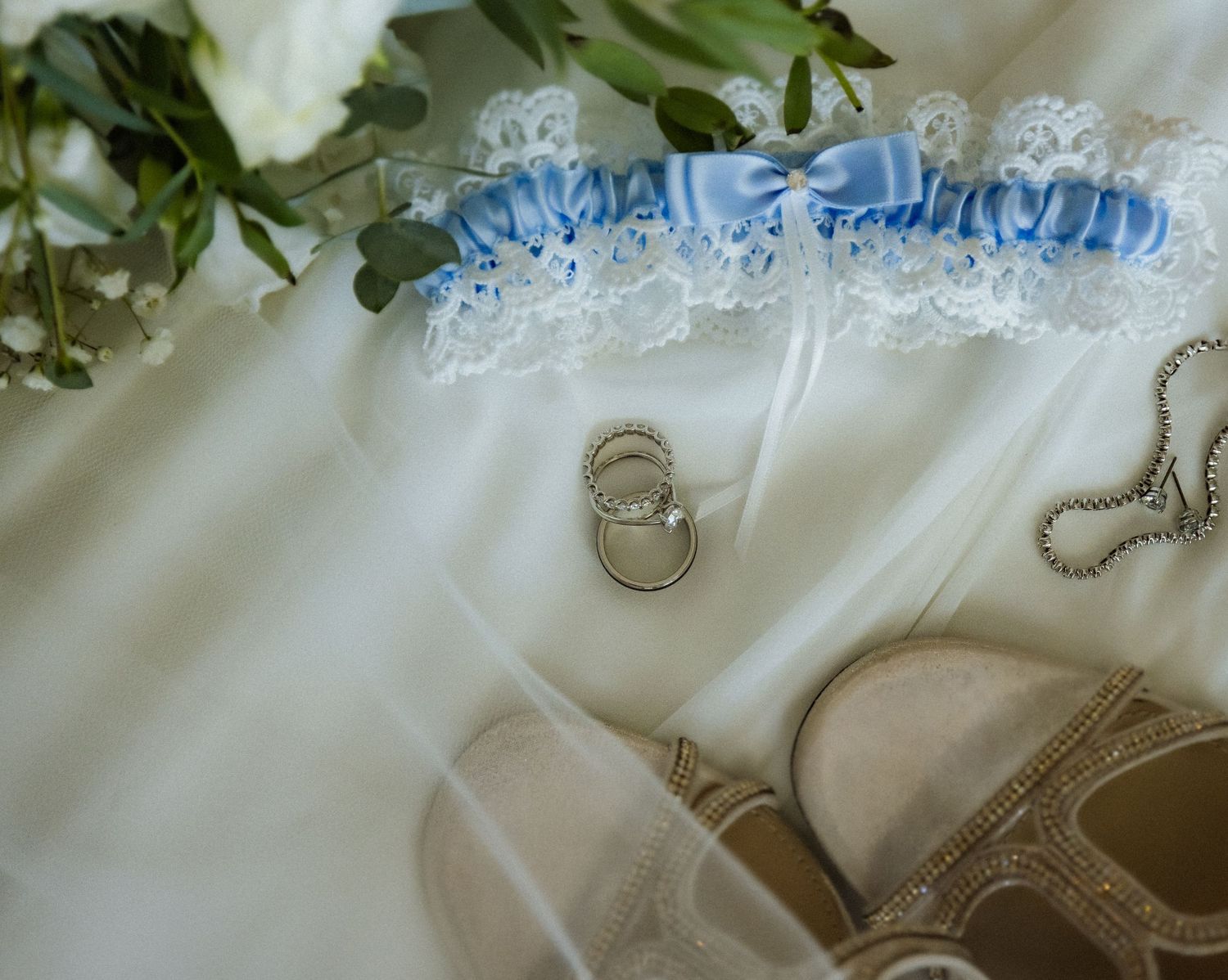 Close-up detail of a white wedding garter with blue trim and delicate lace pattern.
