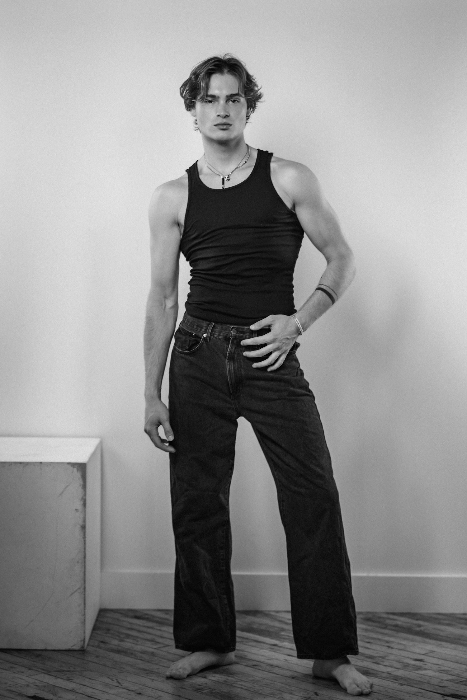 Fashion portrait series in black tank top and wide-leg pants against white background.