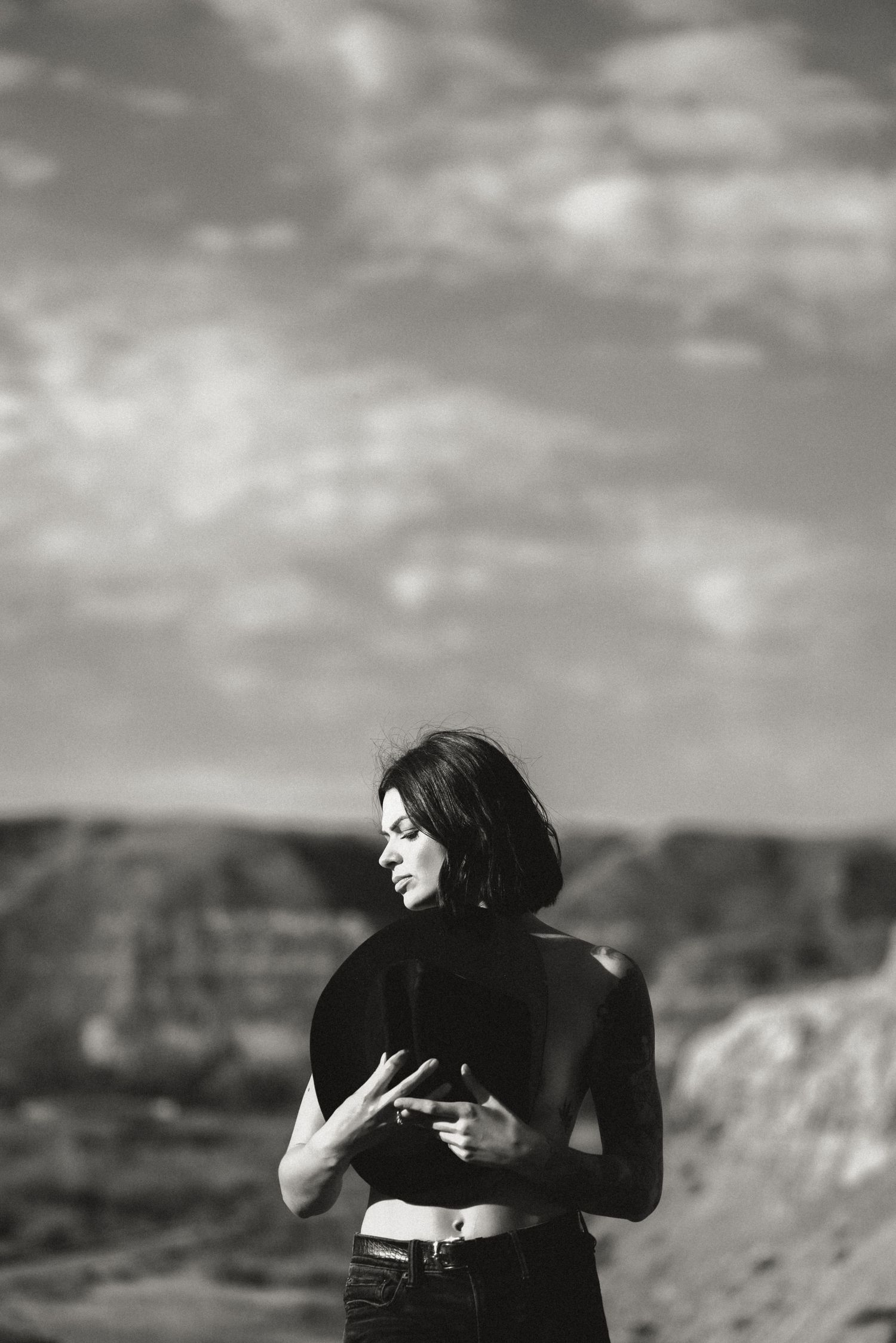 Dramatic black and white portrait series with mountains and cloudy sky in background.