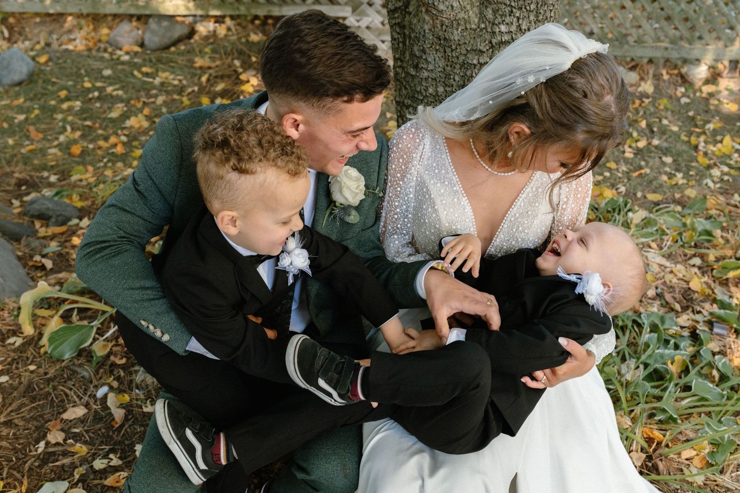 Intimate wedding moments captured on fallen autumn leaves under trees.
