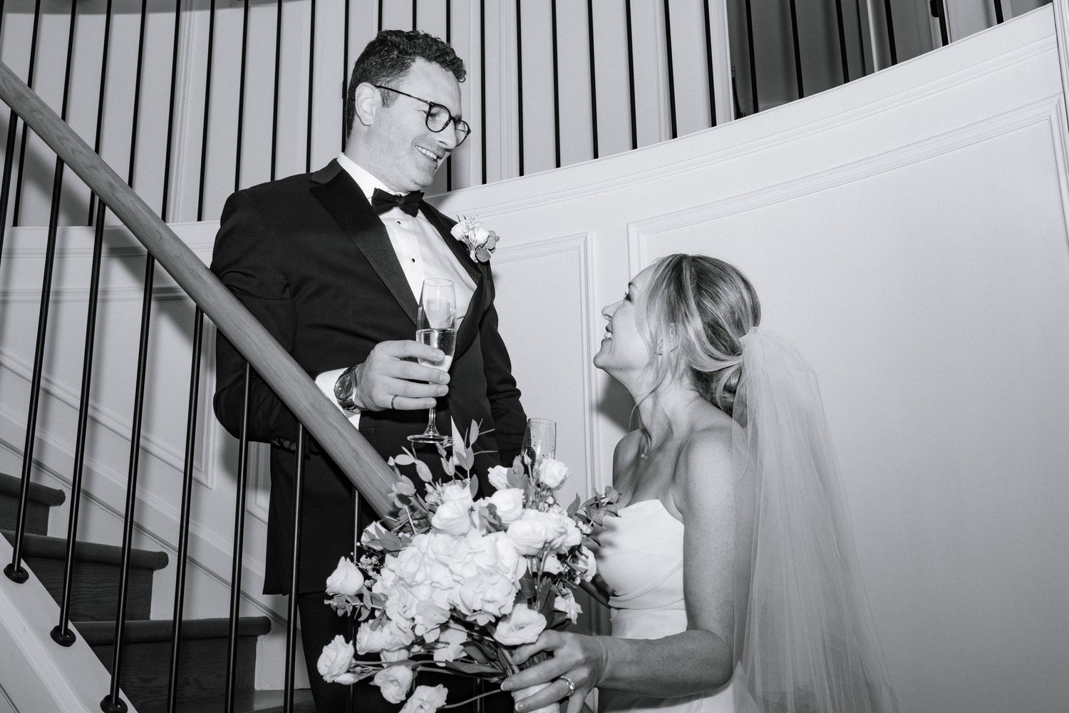Black and white wedding photos show romantic moments between newlyweds on a staircase.