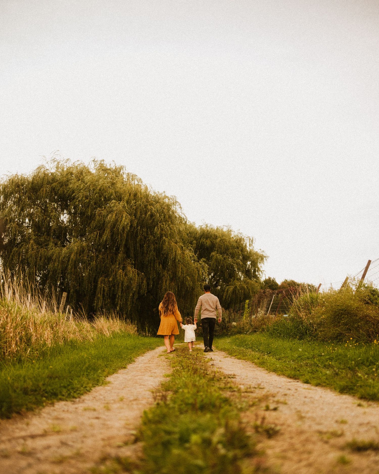 Distant view of people walking along a countryside path at sunset.