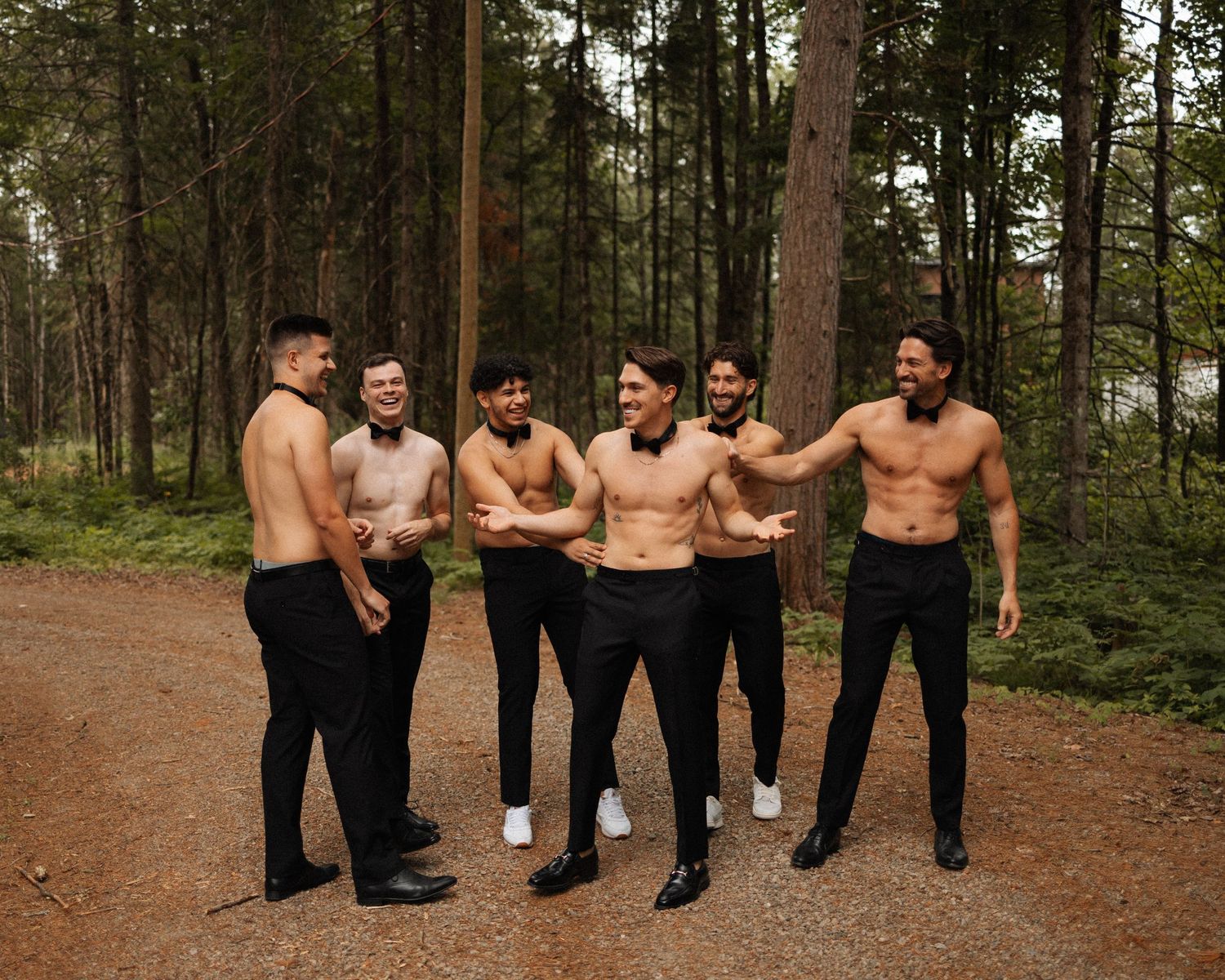 Group walking through a pine forest path wearing formal attire.