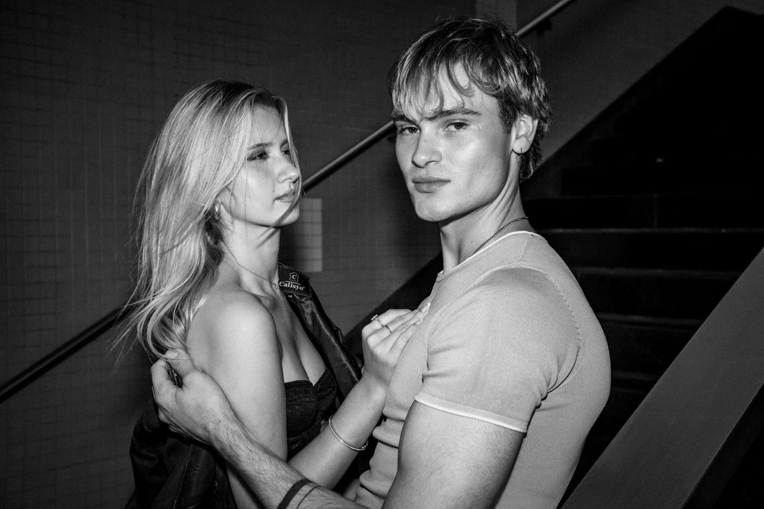 A couple shares an intimate black and white moment in a dimly lit setting.