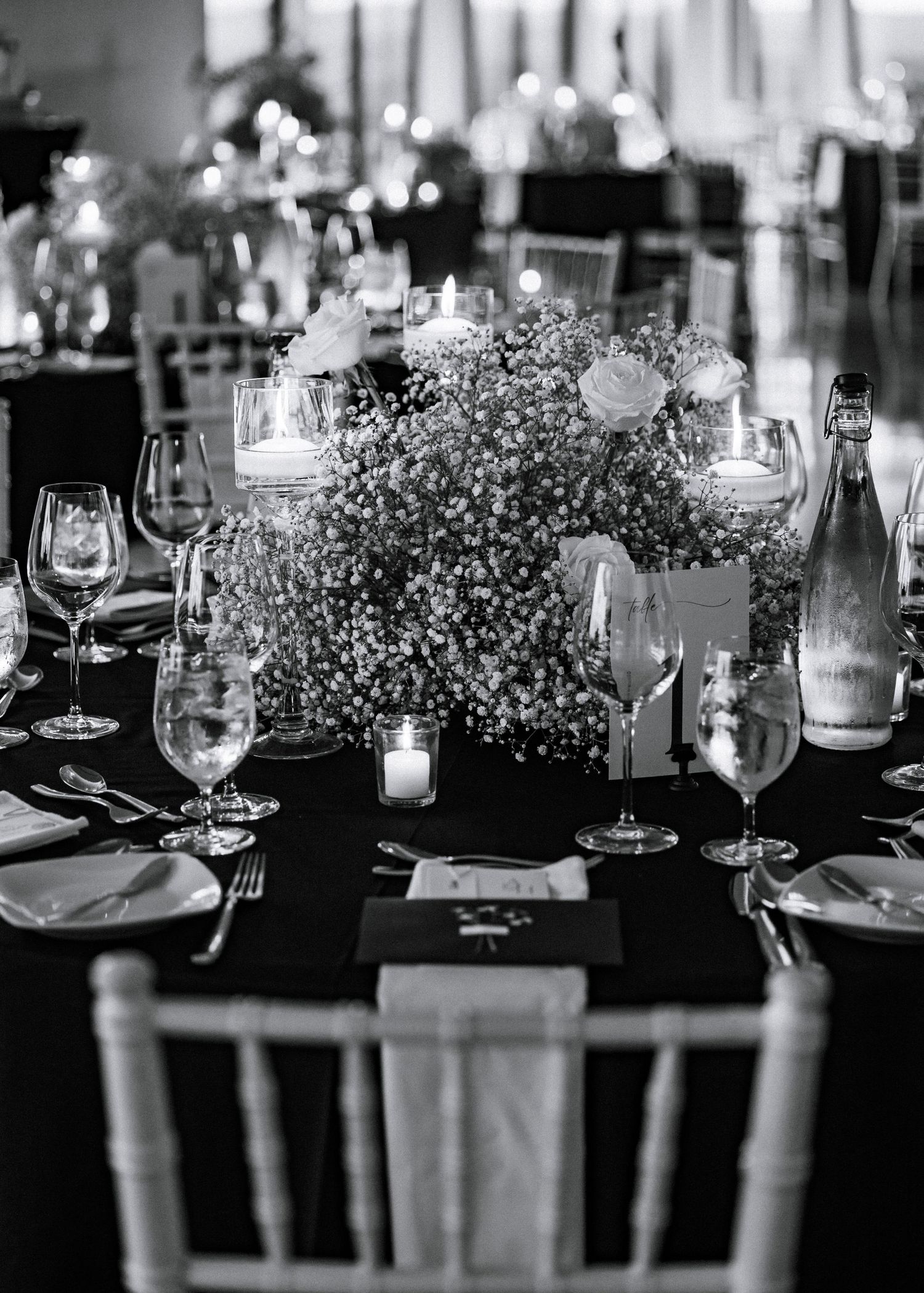 Elegant wedding reception table setting with baby's breath centerpieces and wine glasses.