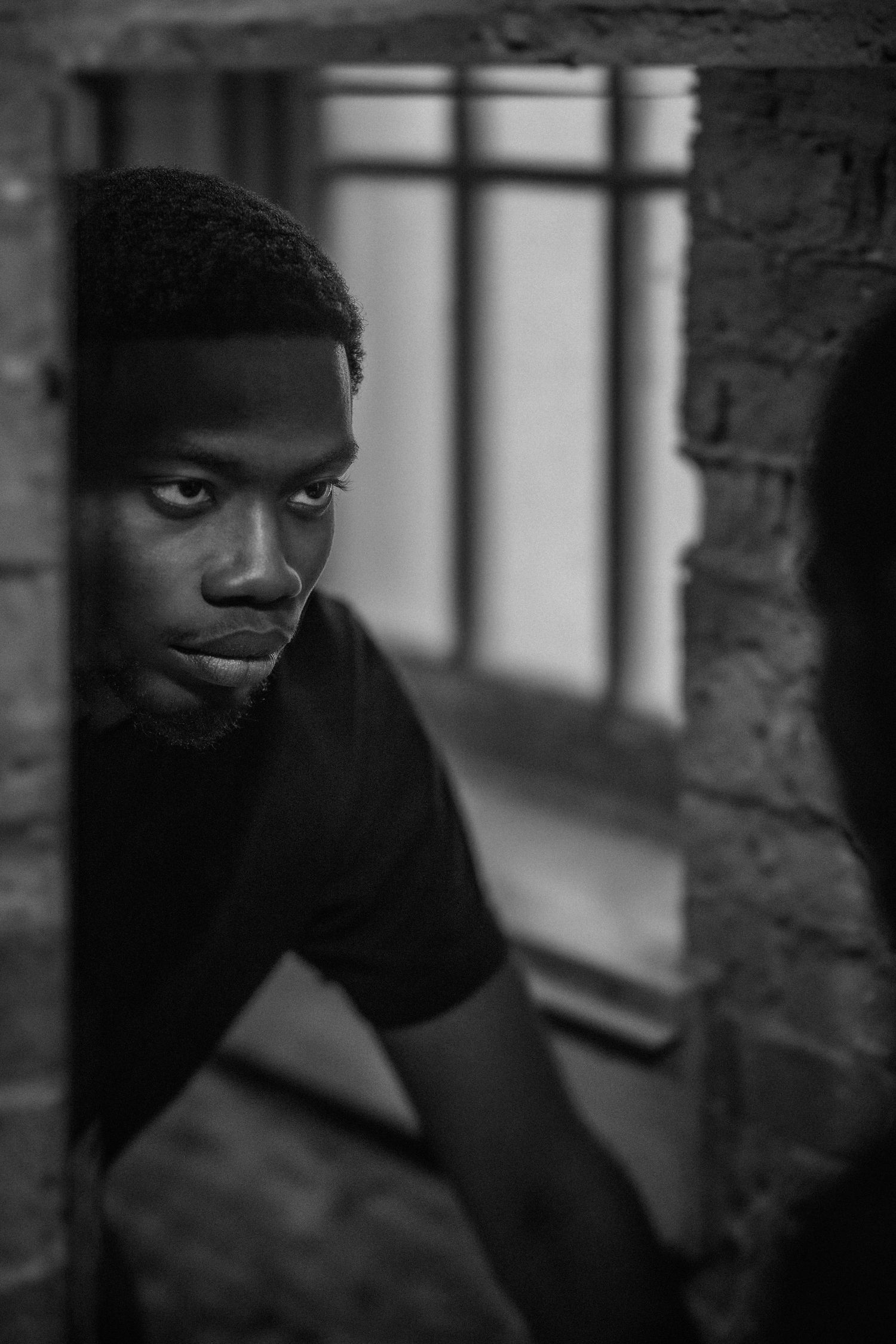 Artistic black and white portrait series showing contemplative expressions through window bars.