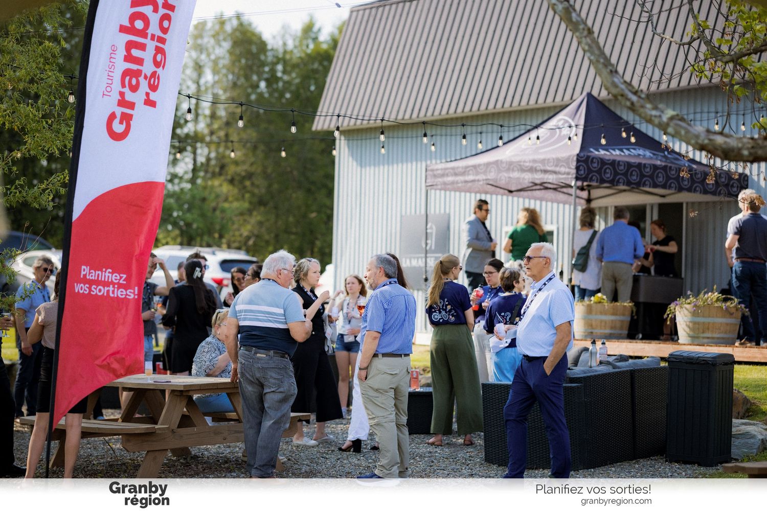 People mingling under tents at an outdoor market or community gathering.