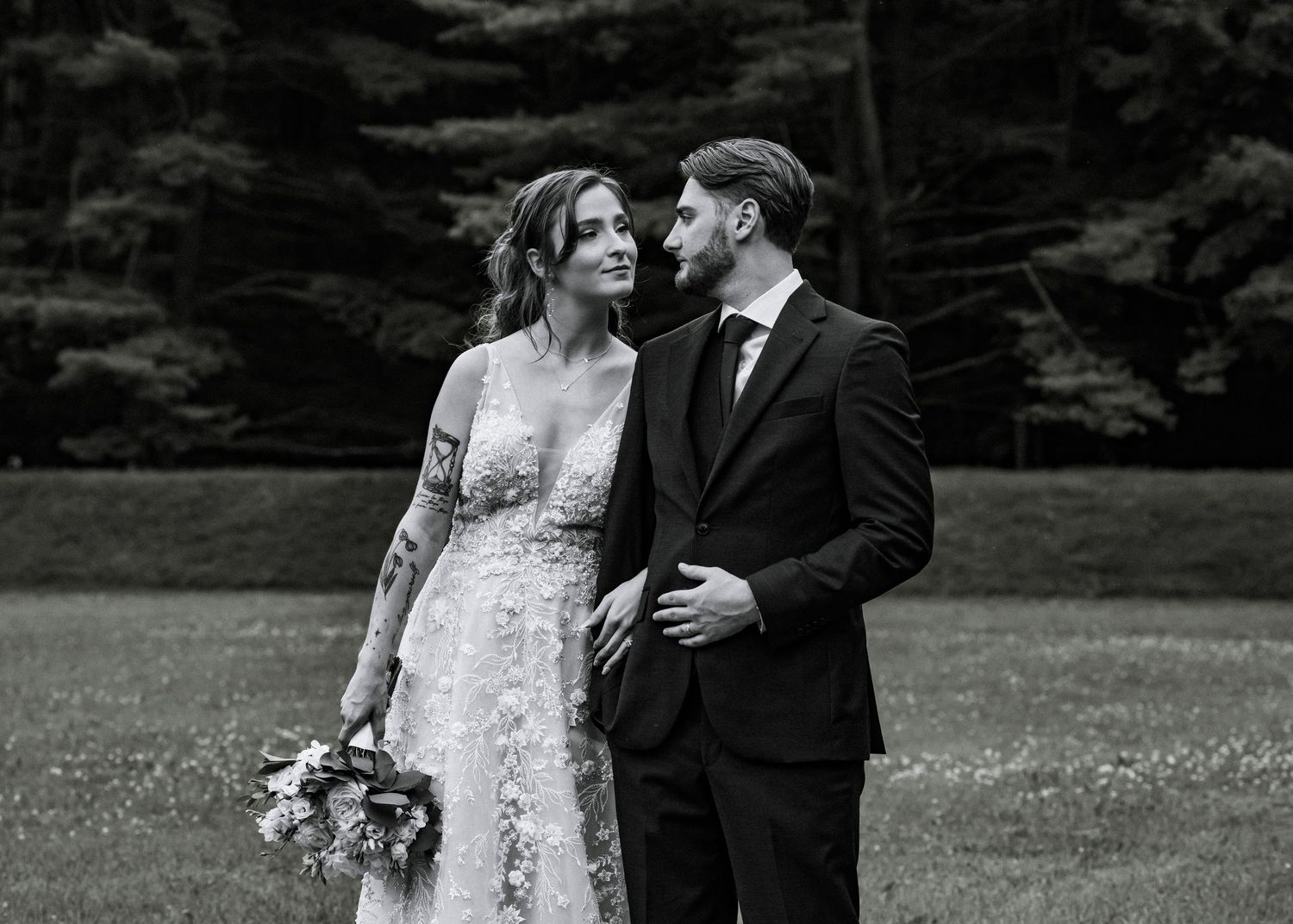 A black and white photo of a couple sharing a romantic moment at their outdoor wedding.