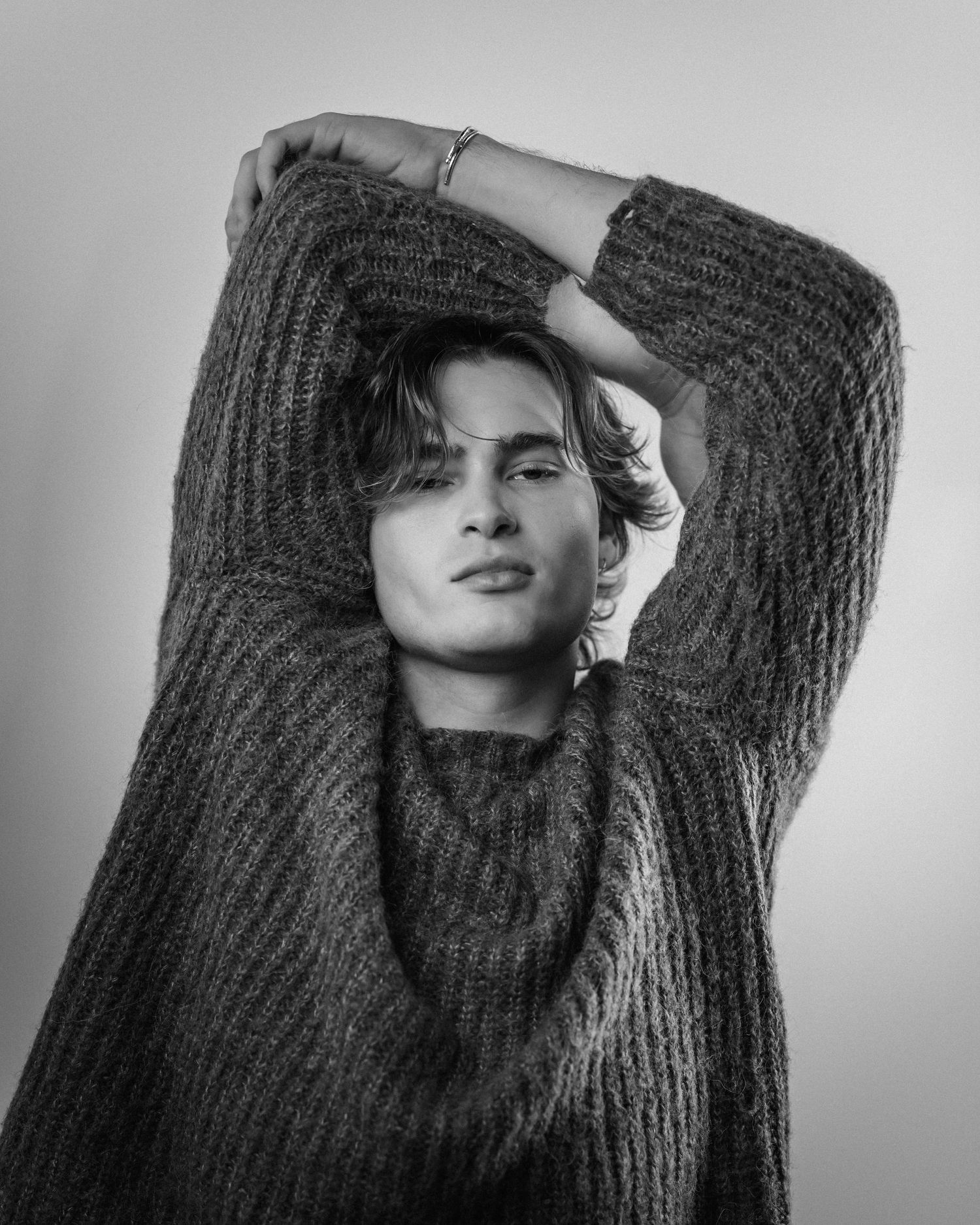 Artistic black and white photos of model in chunky knit sweater.
