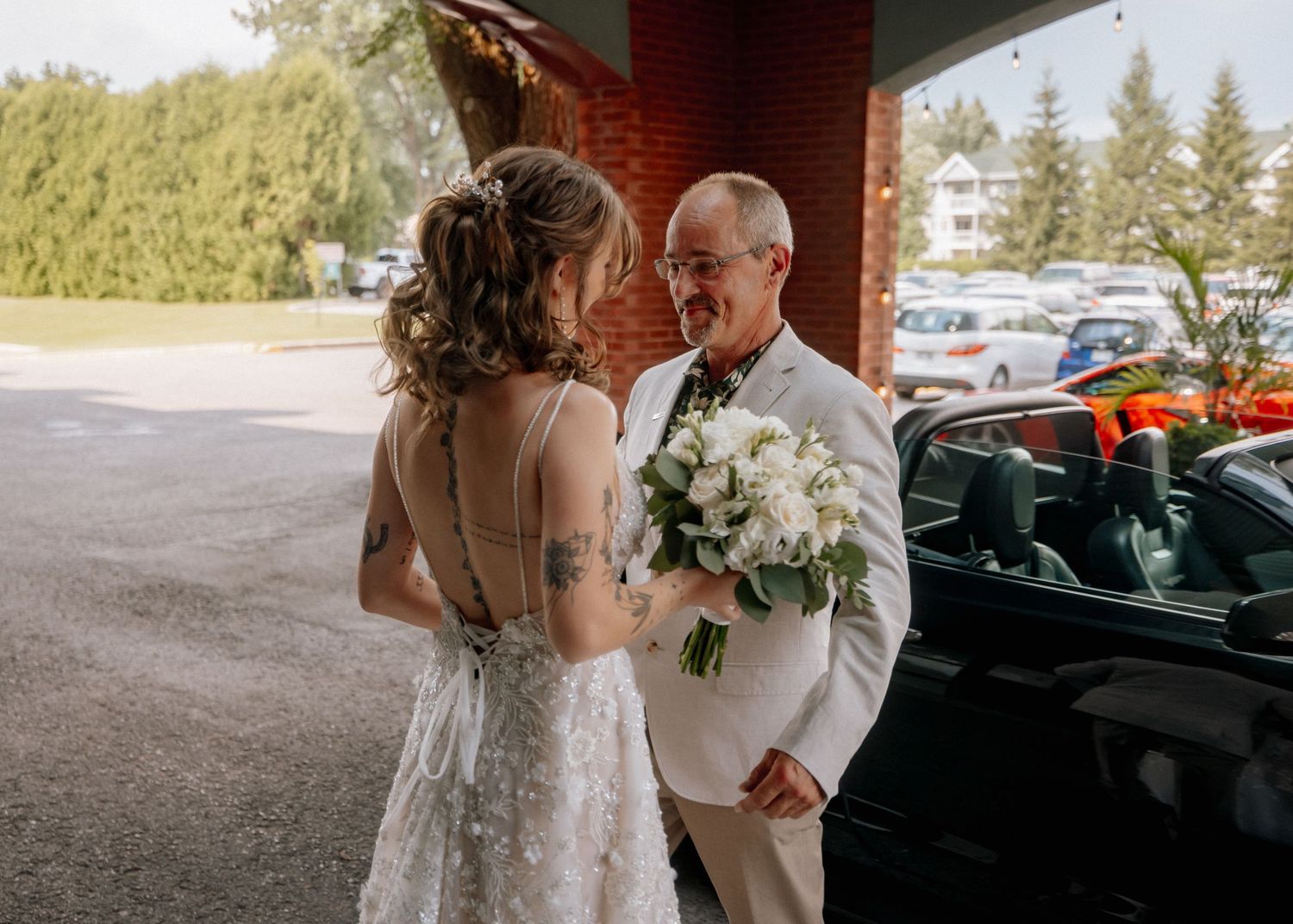 Wedding ceremony setup with white chairs and brick building in background.