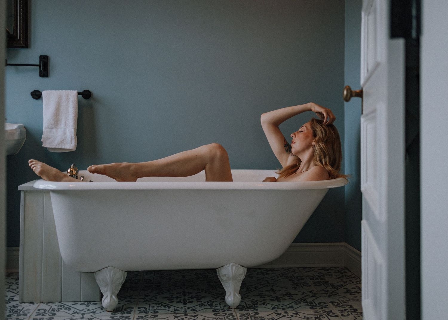 Vintage clawfoot bathtubs in a row against a blue-grey wall in a bathroom interior.